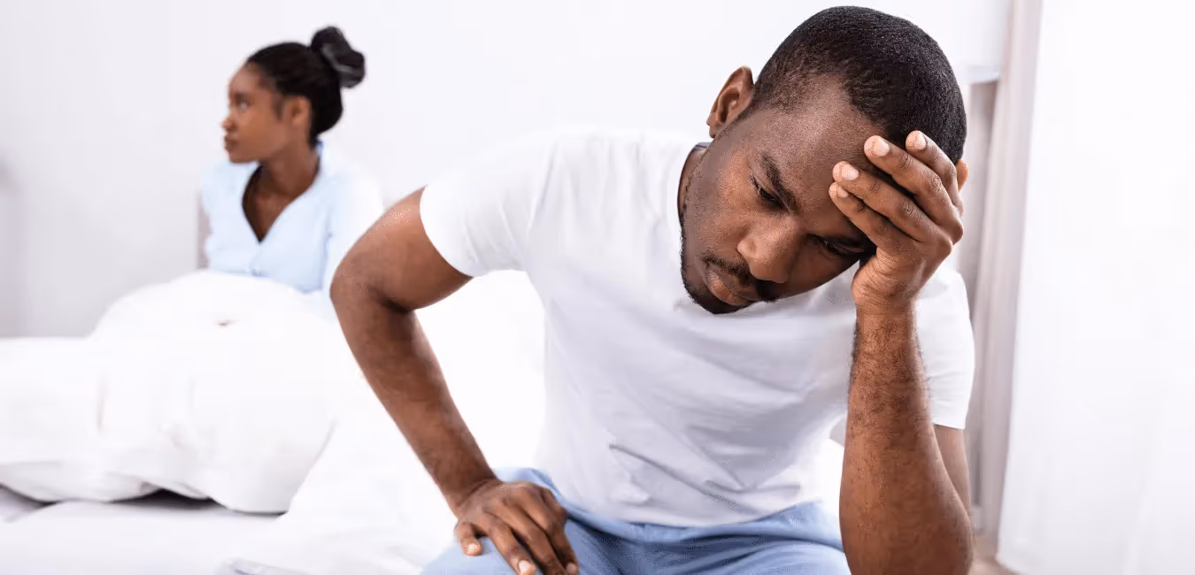 African couple wearing shirt looking unhappy on their bed