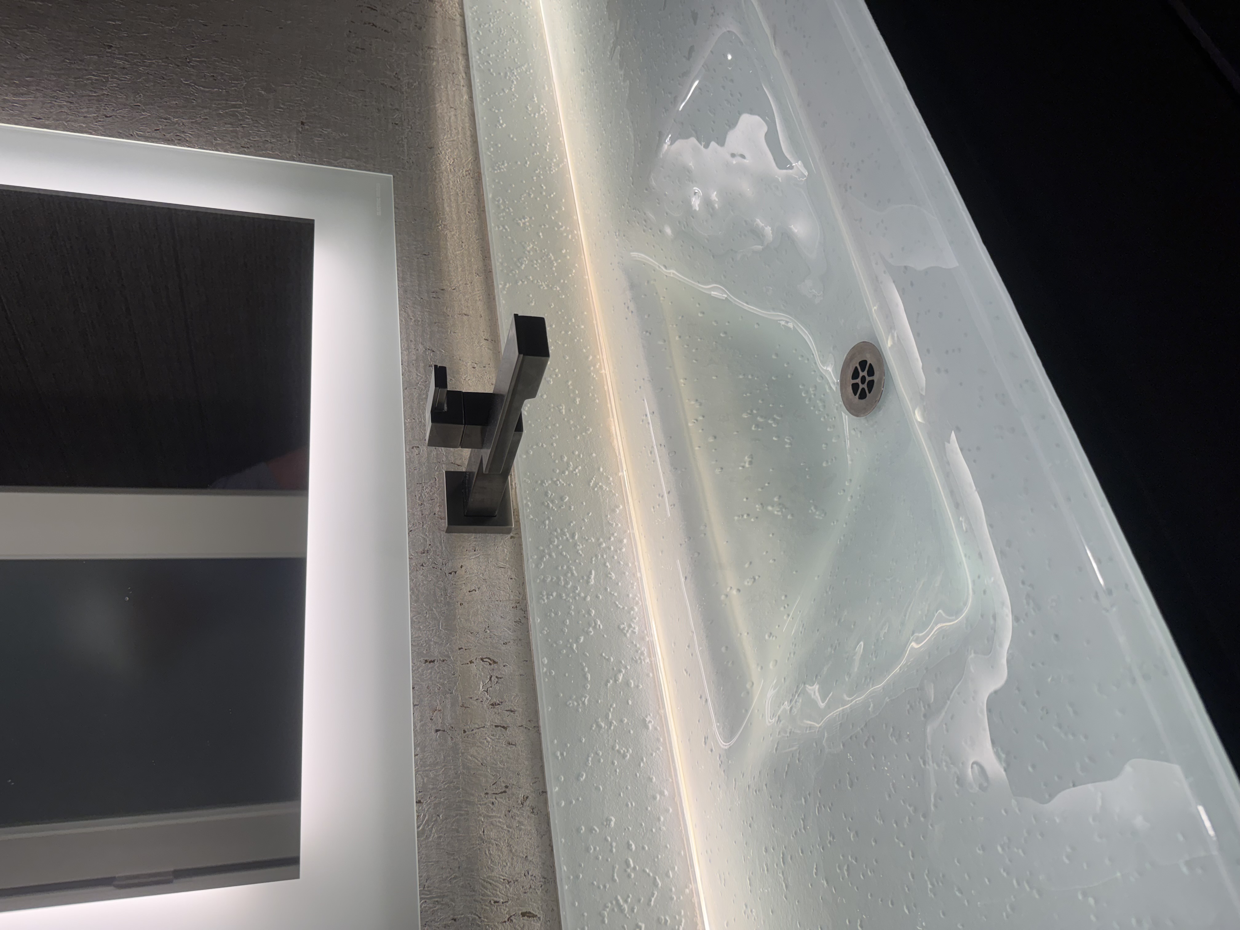 Modern bathroom glass integral sink slab with led backlighting.