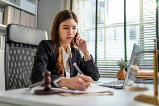 debt collection lawyer talking to small business owner on phone and taking notes as she sits at her office desk