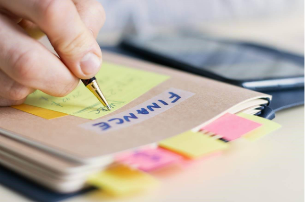 small business folder labeled finance with businessman writing on yellow note attached for folder
