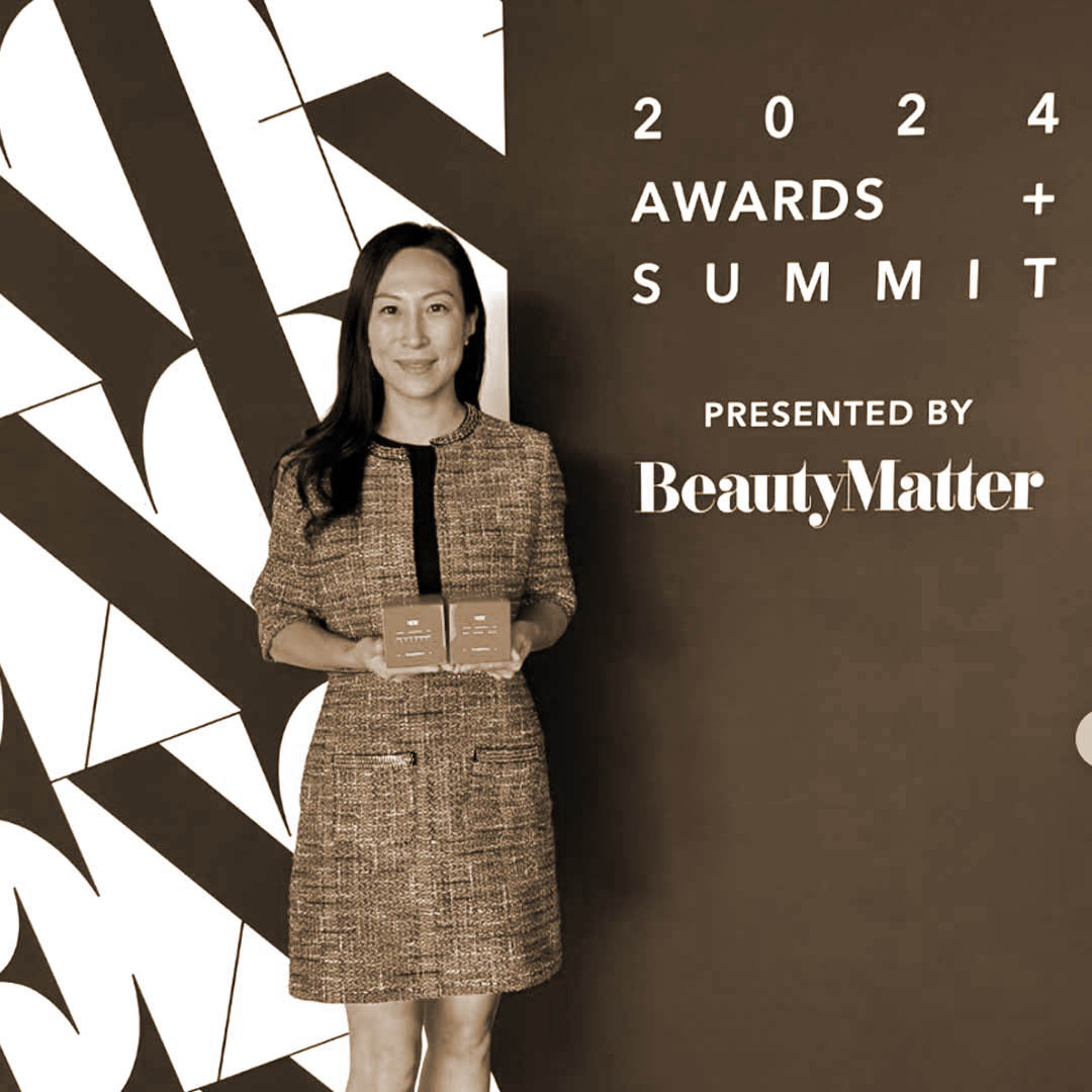 2024 BeautyMatter Awards winner hlding trophy standing by a wall