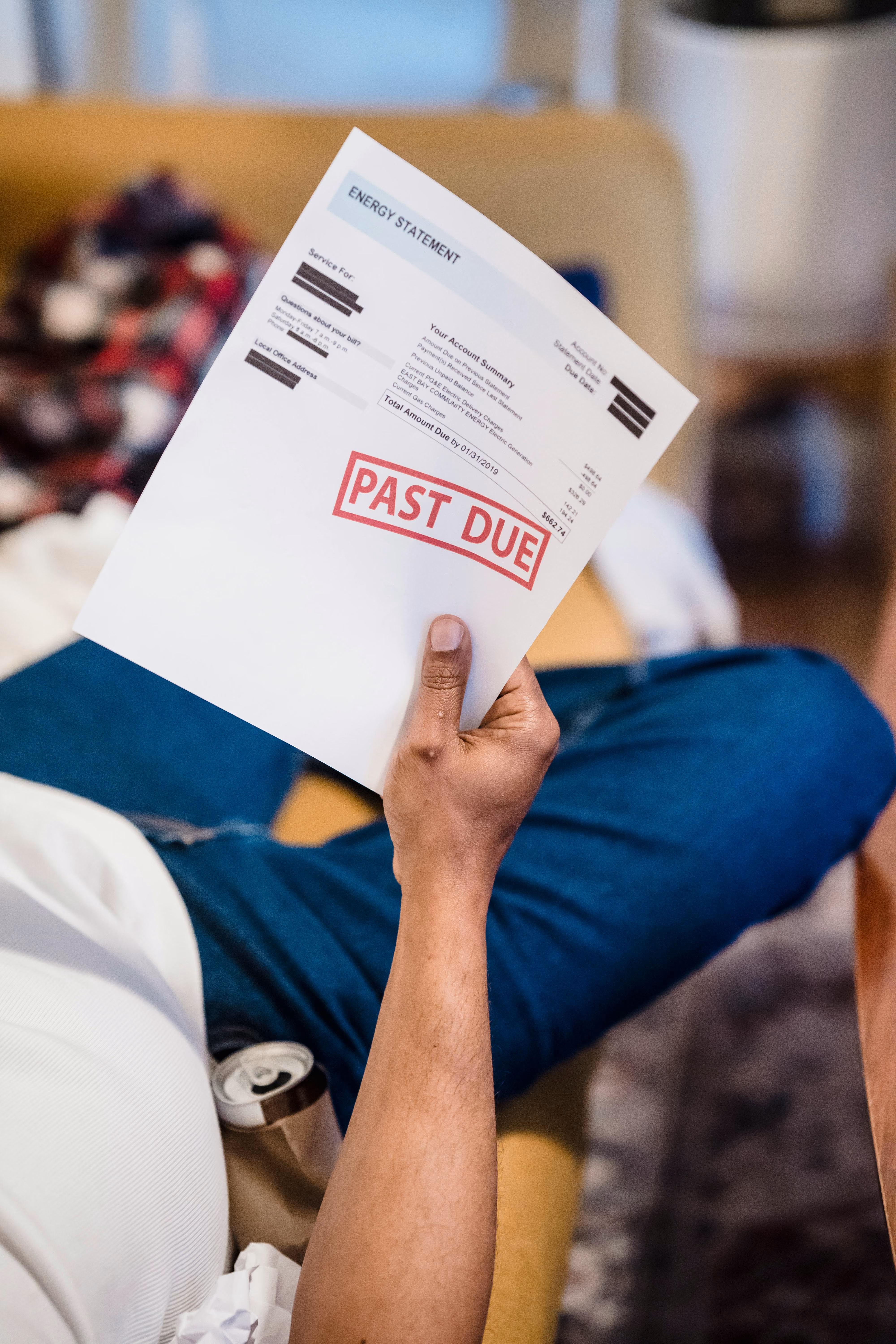 Person holding an energy statement with a large red 'PAST DUE' stamp on it.