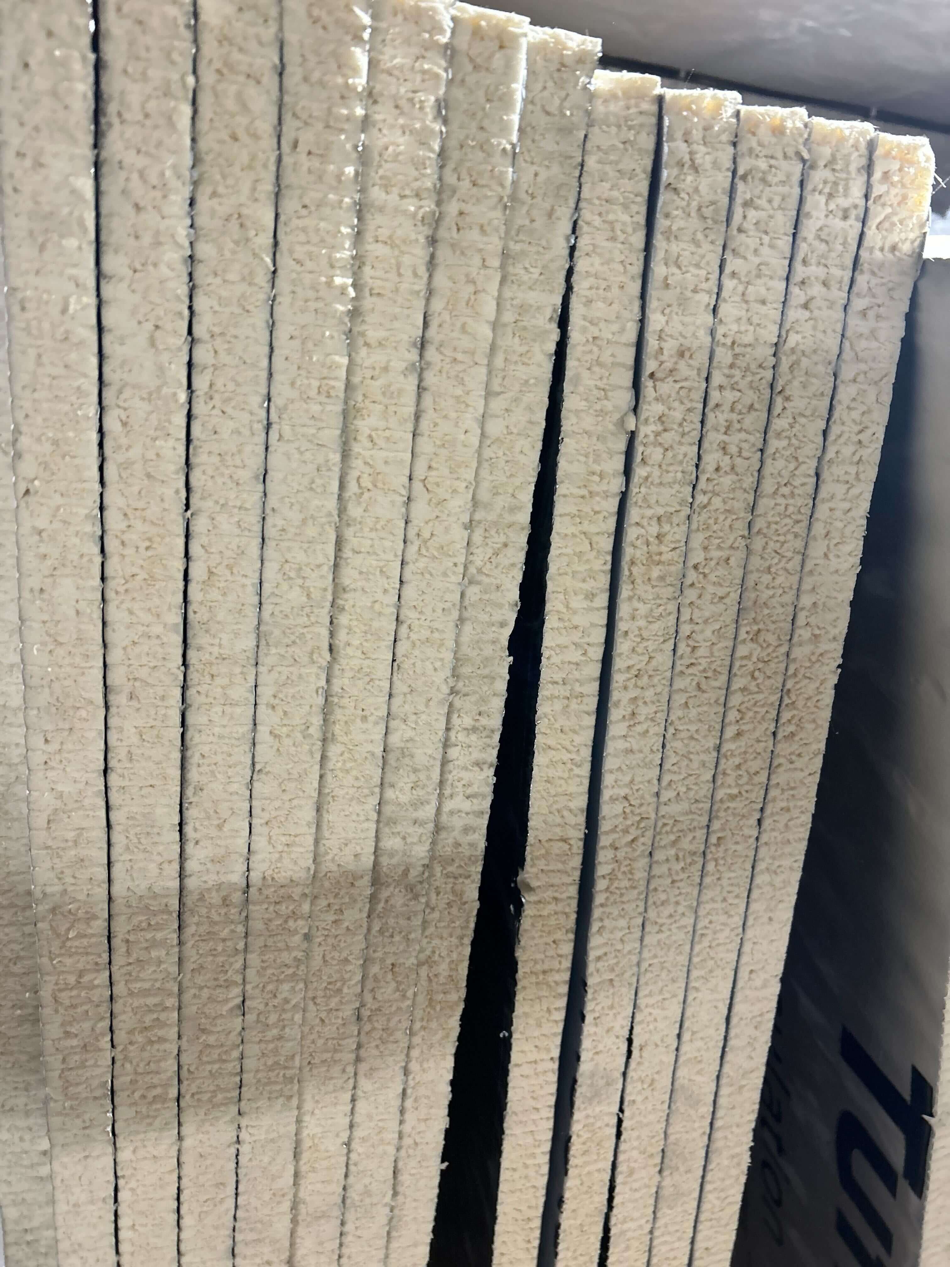 Stack of beige rigid foam board insulation panels arranged vertically.