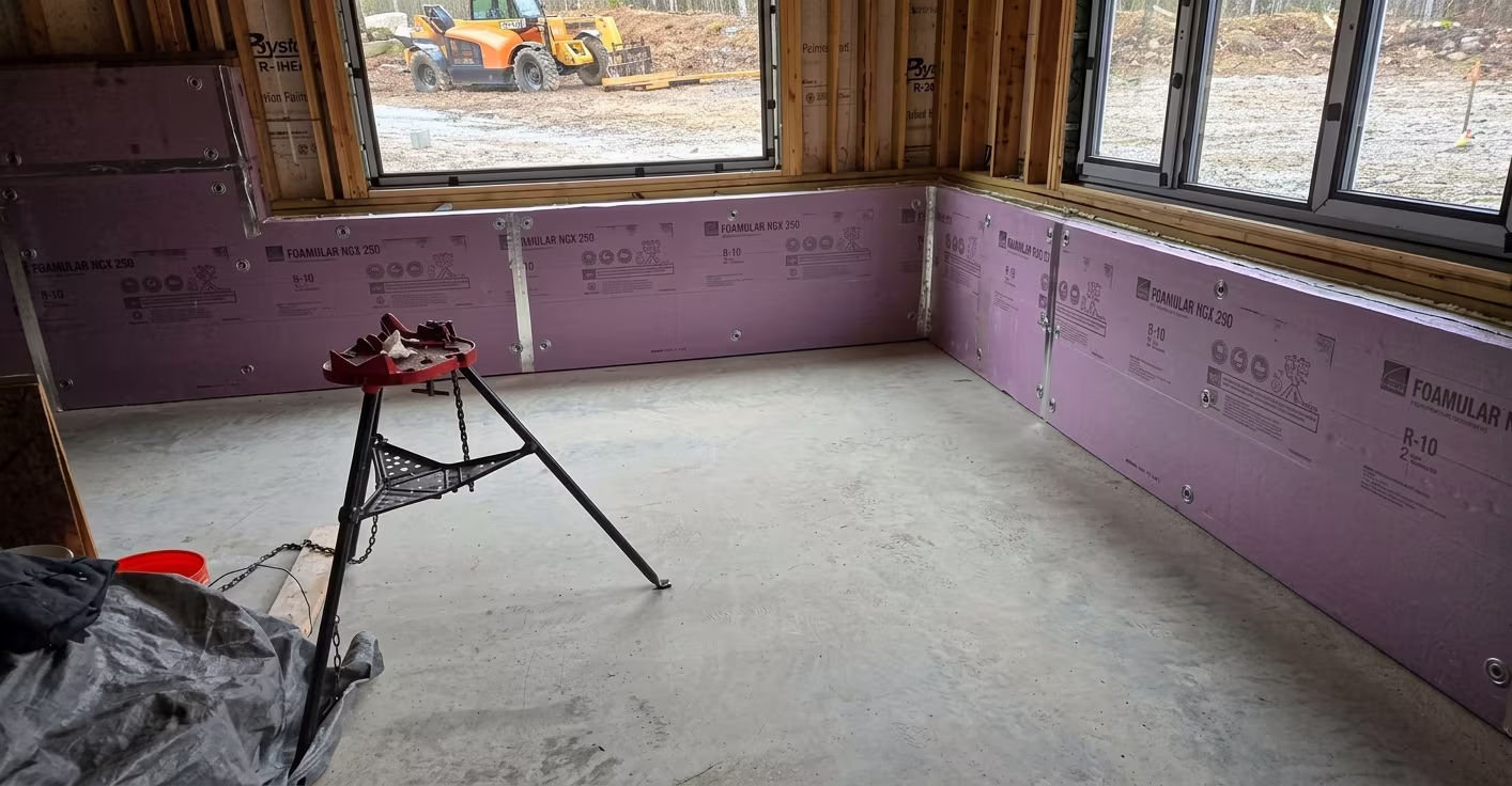 Unfinished room with concrete floor, construction insulation on walls, and a pipe stand in the center.