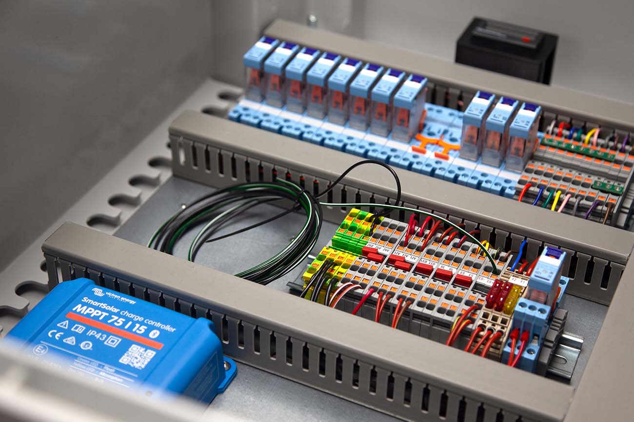 Close-up of a completed wiring control panel featuring labelled terminal blocks, multiple relays, neatly routed wiring, and a Victron SmartSolar charge controller — part of Tec-Stop’s precision-built electrical assemblies.