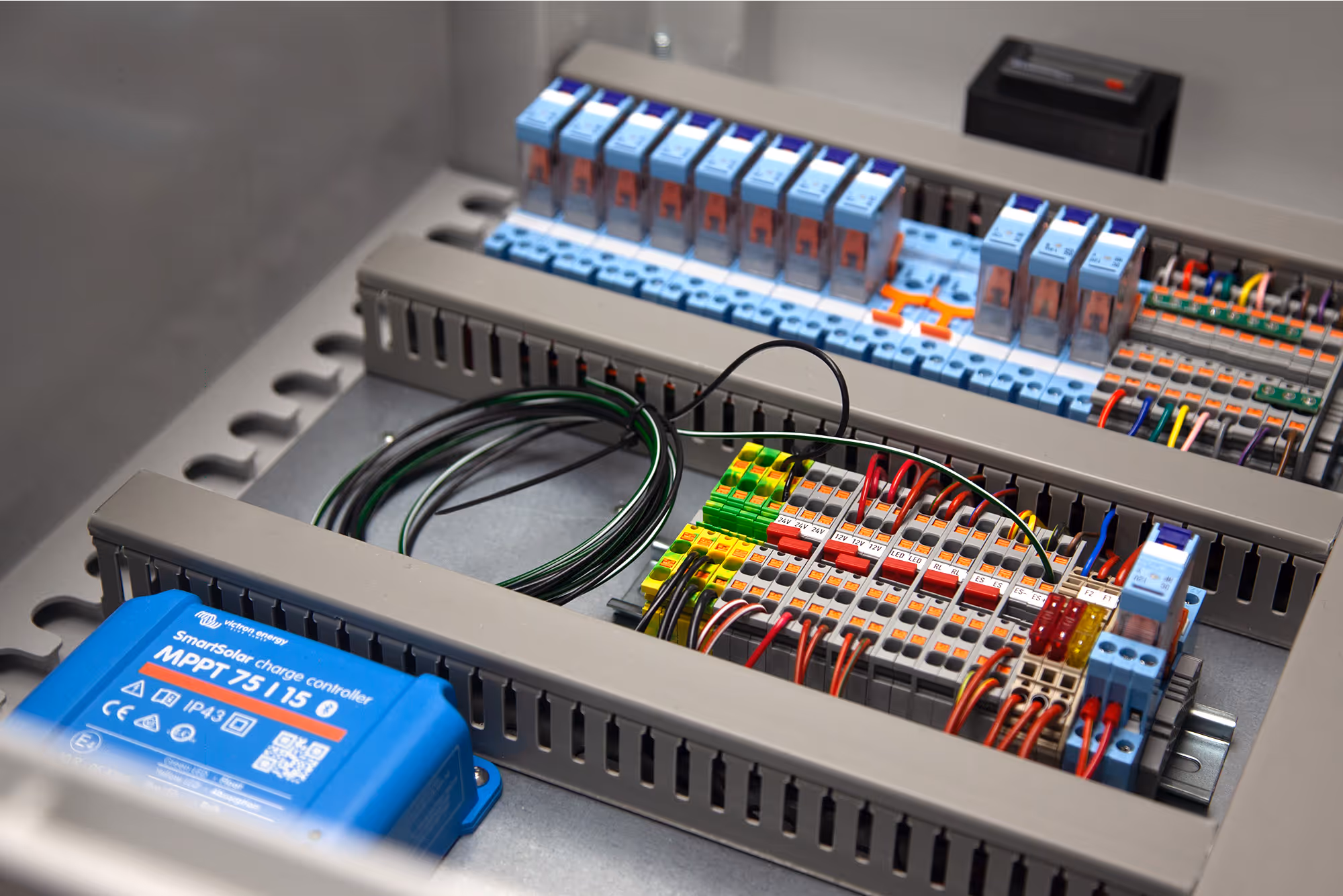 Internal view of a custom electrical control panel showing circuit breakers, relays, terminal blocks and distribution board wiring