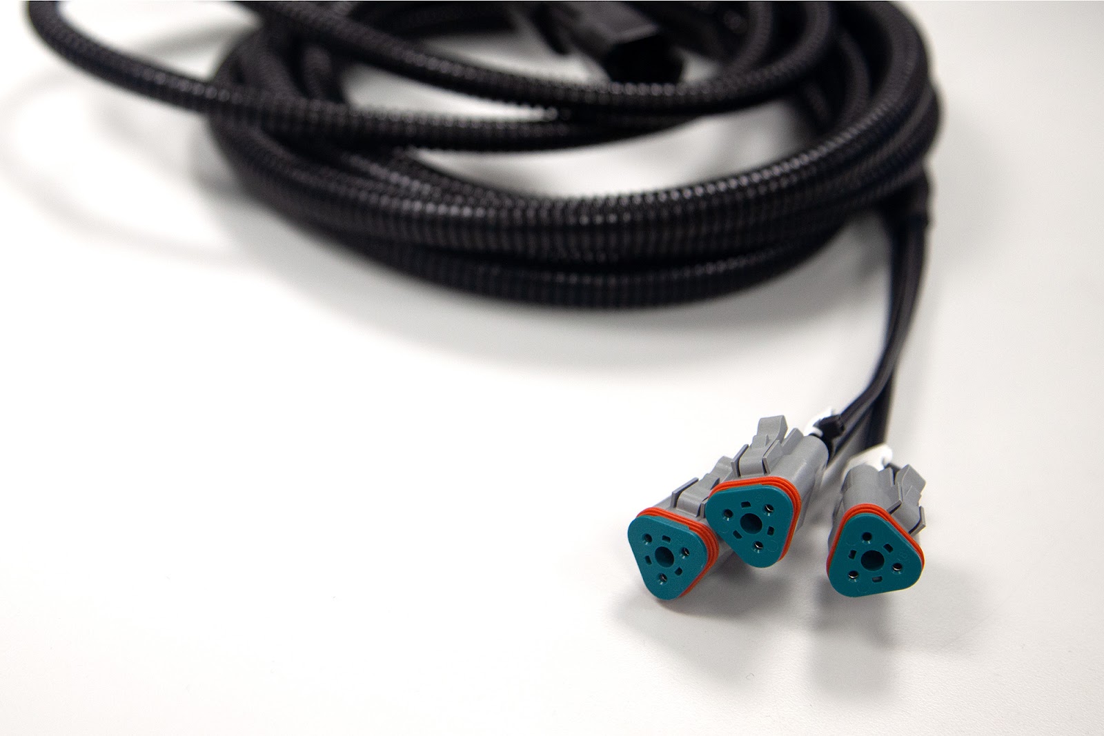 Close-up of a completed Tec-Stop cable loom with three sealed Deutsch-style connectors.