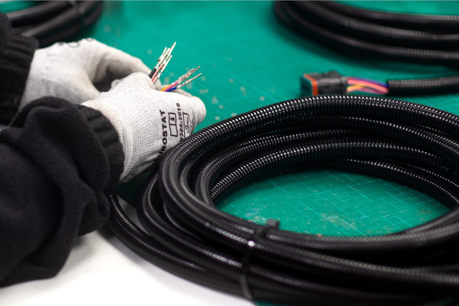 Gloved Tec-Stop technician preparing multi-core wires inside a heavy-duty braided cable loom.