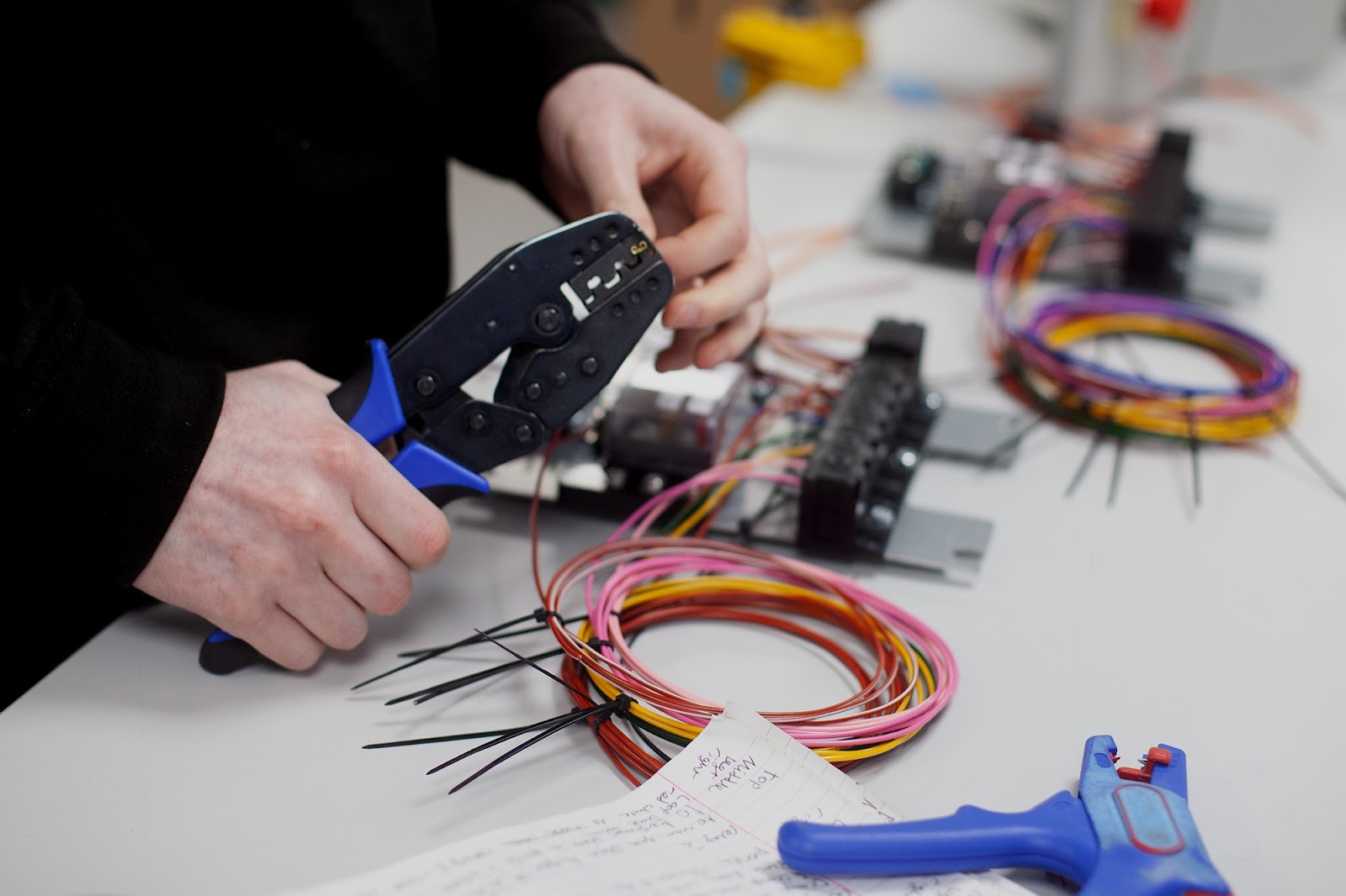 Engineer assembling OEM wiring harnesses with professional crimping tools at Tec-Stop