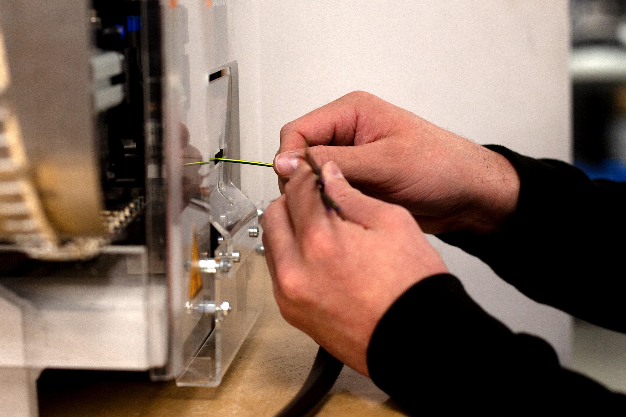 Technician feeding cable into an automated wire cutting and stripping machine at Tec-Stop