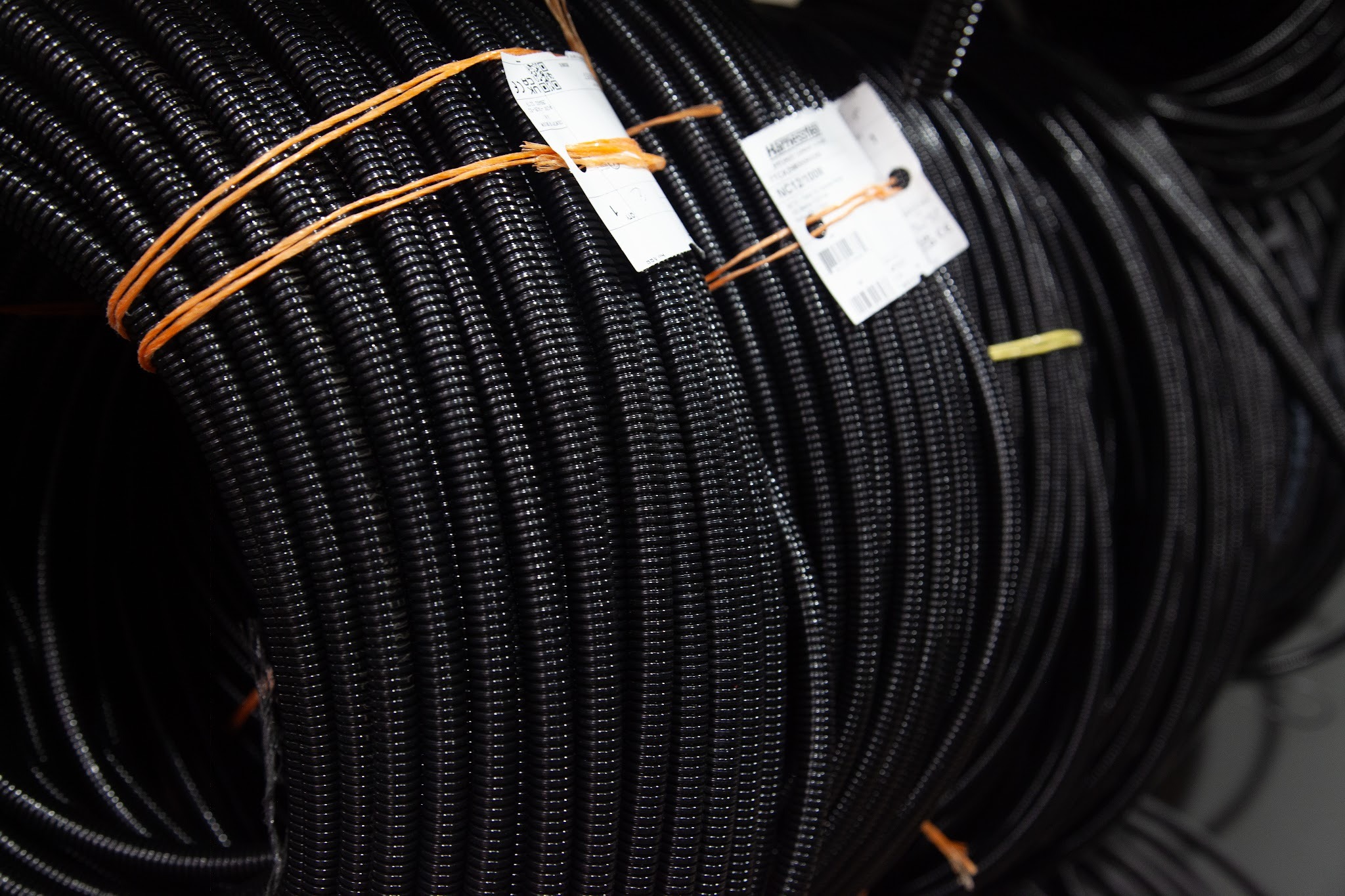 Coiled cable conduit and protective sleeving used in wiring harness manufacturing and cable assembly production