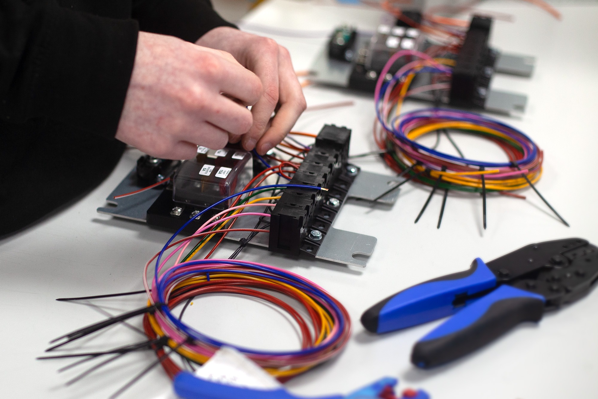 Cable assembly technician wiring connectors and components on a workbench with tools and prepared cables