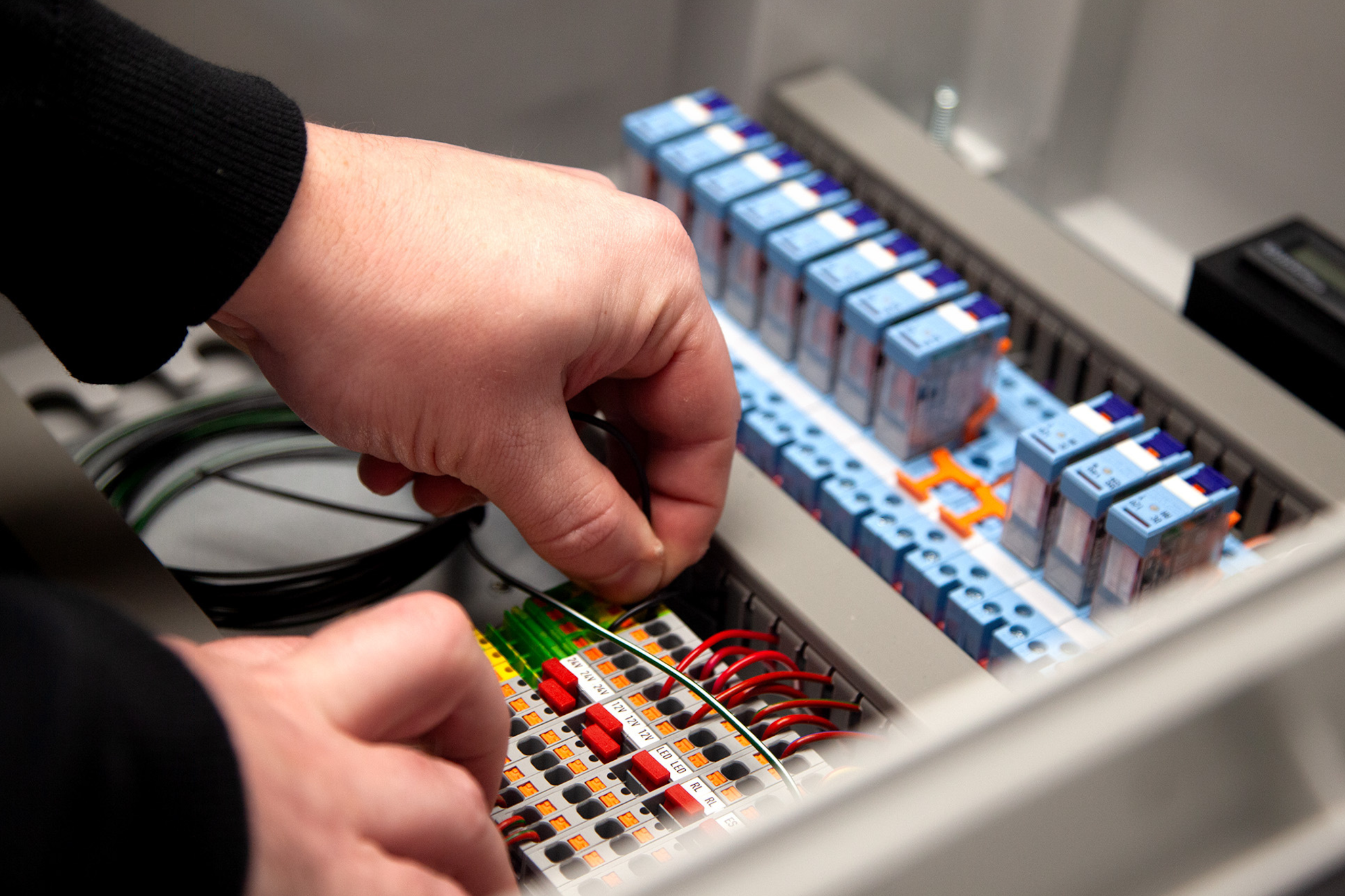 Engineer wiring an industrial electrical control panel during panel assembly