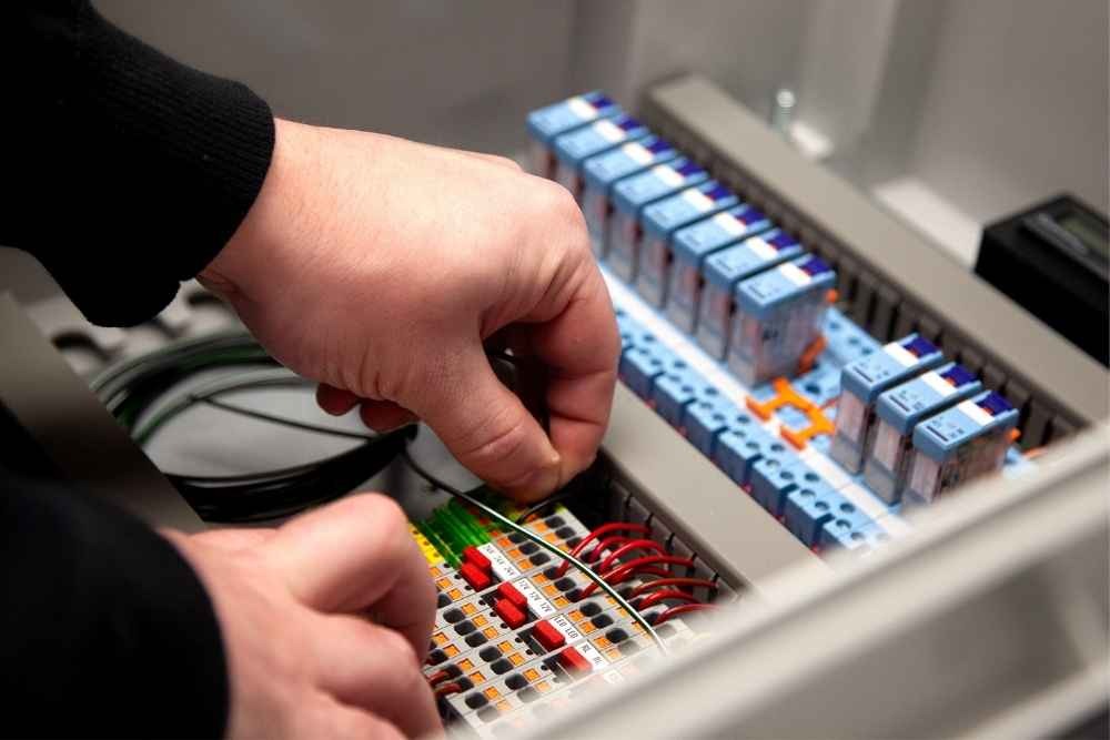 Technician wiring electrical components inside a control panel enclosure
