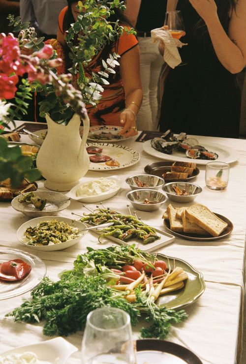 Flowers, plates, and glasses layed on top of a beige table cloth
