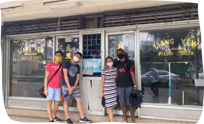 Four people wearing masks standing in front of Liang Yew Beauty Salon with glass windows and yellow signage.