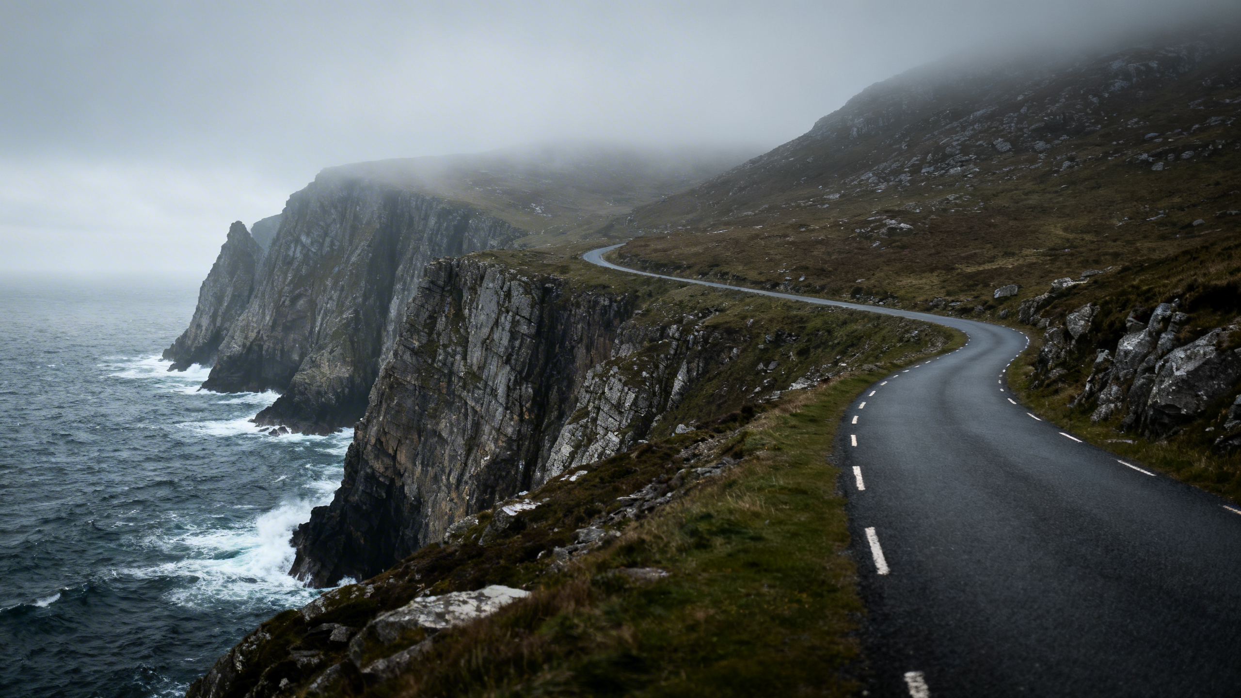 Narrow road curving along the Atlantic Drive on Achill Island, County Mayo, with sea cliffs falling away to the left