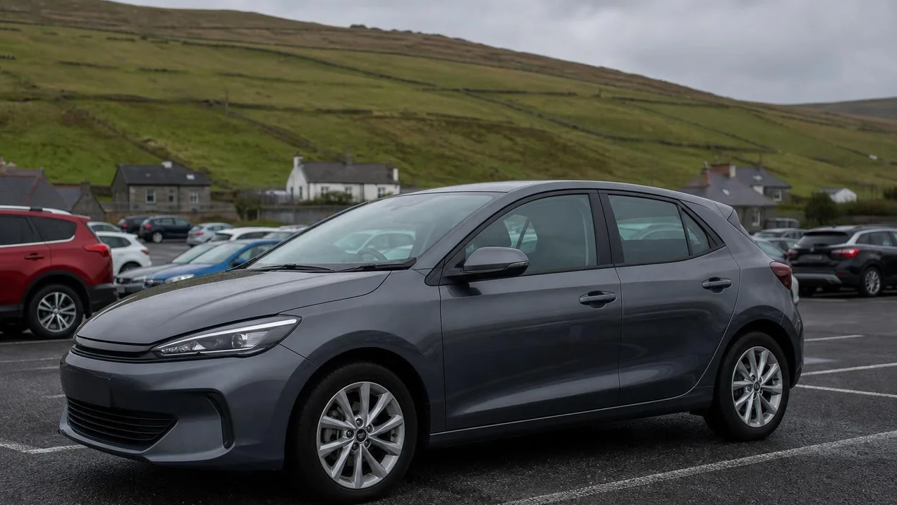 Modern hatchback parked in a compact Irish rental car lot with other cars visible in the background, overcast day, no branding on vehicles. Natural documentary style.