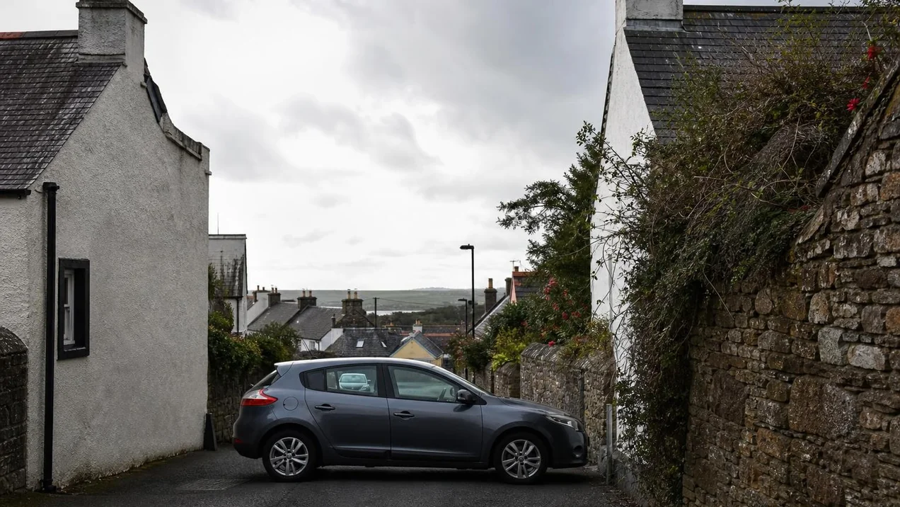 A medium-sized hatchback parked on a narrow street in a small Irish town, fitting comfortably between stone walls. Overcast day. Documentary style.
