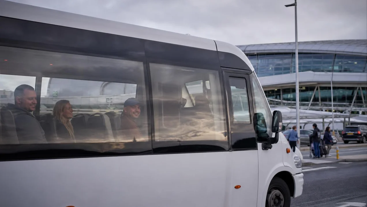 The My Irish Cousin shuttle bus at Dublin Airport, arriving passengers visible through the window. Overcast day, documentary style.