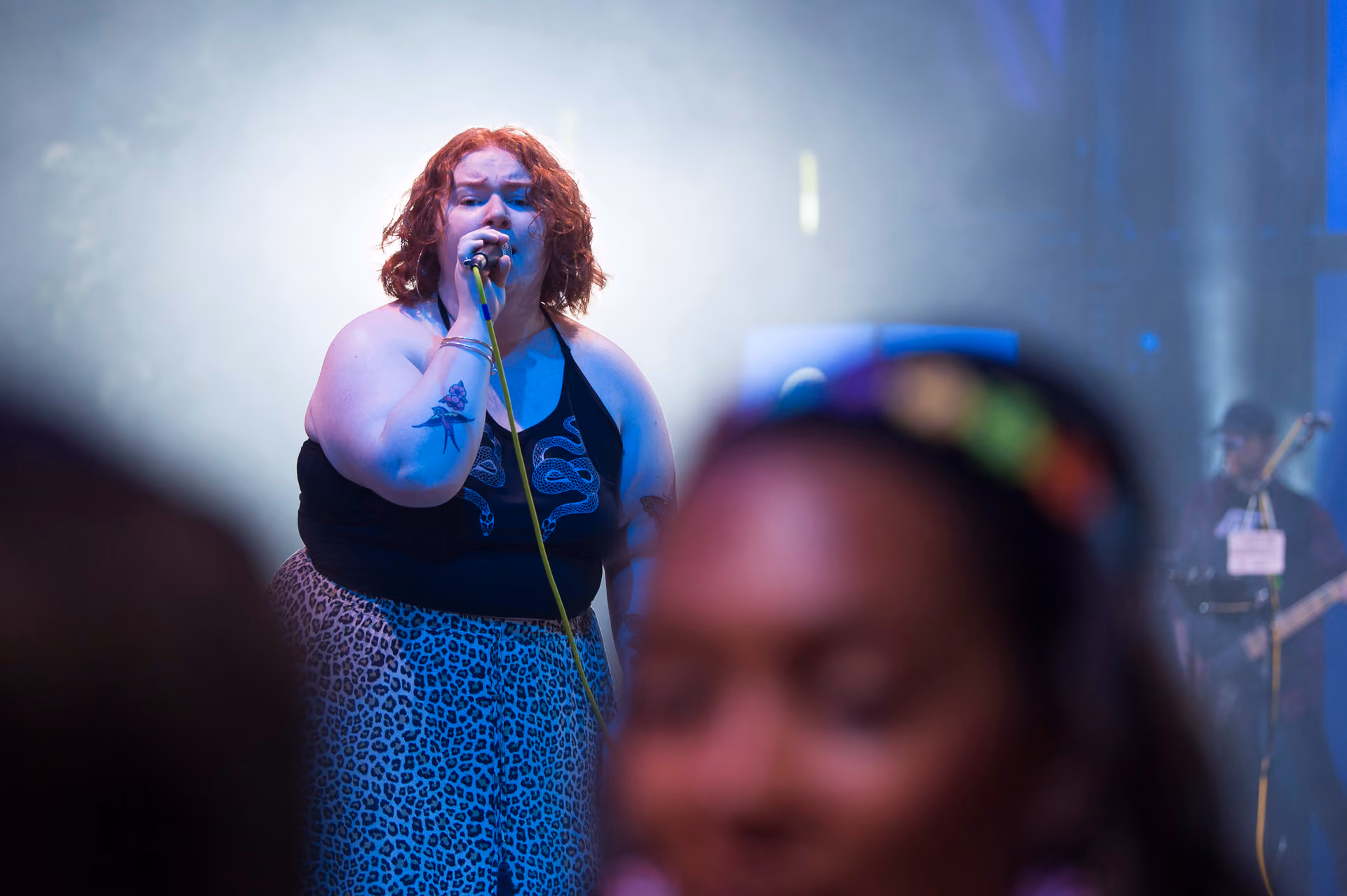A vocalist singing on stage with a live band as guests watch at a company party