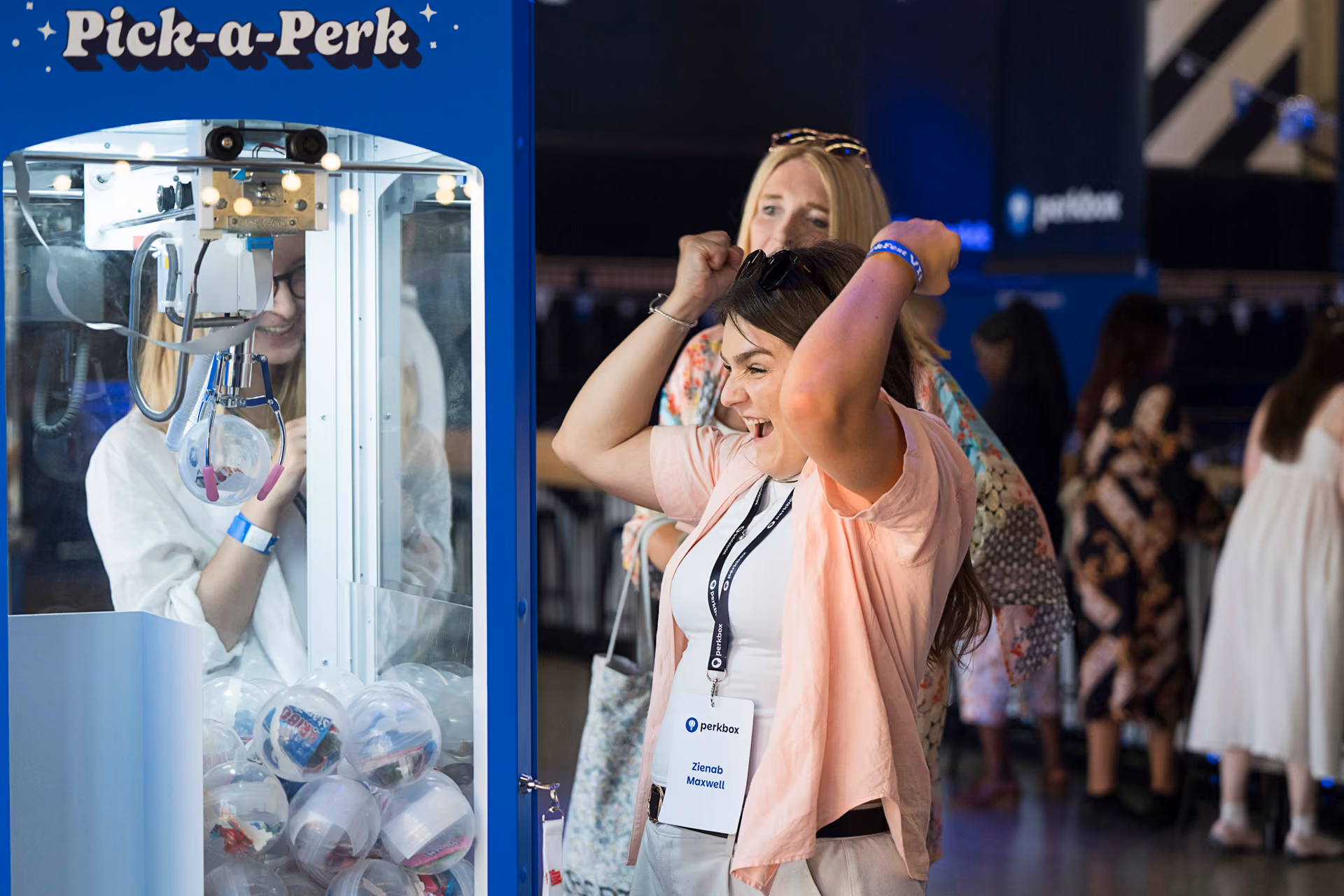 A guest cheering as she plays a branded claw machine game at a company day