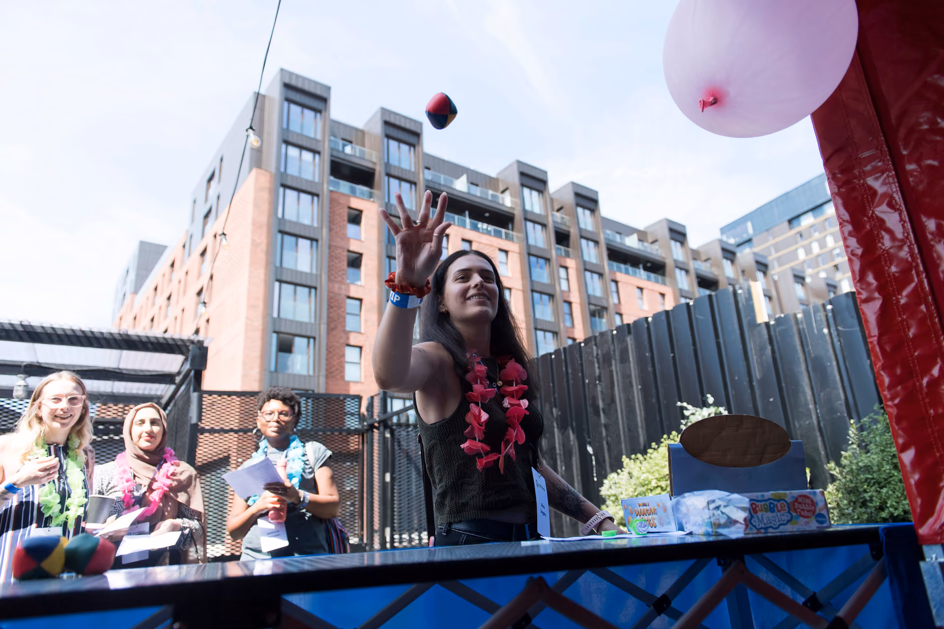 A guest throwing a beanbag at an outdoor game stall during a company summer party