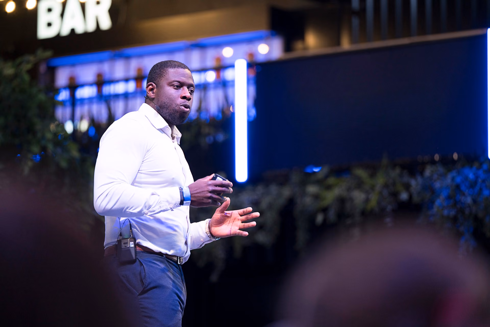 A speaker addressing guests in front of a branded backdrop at a company event