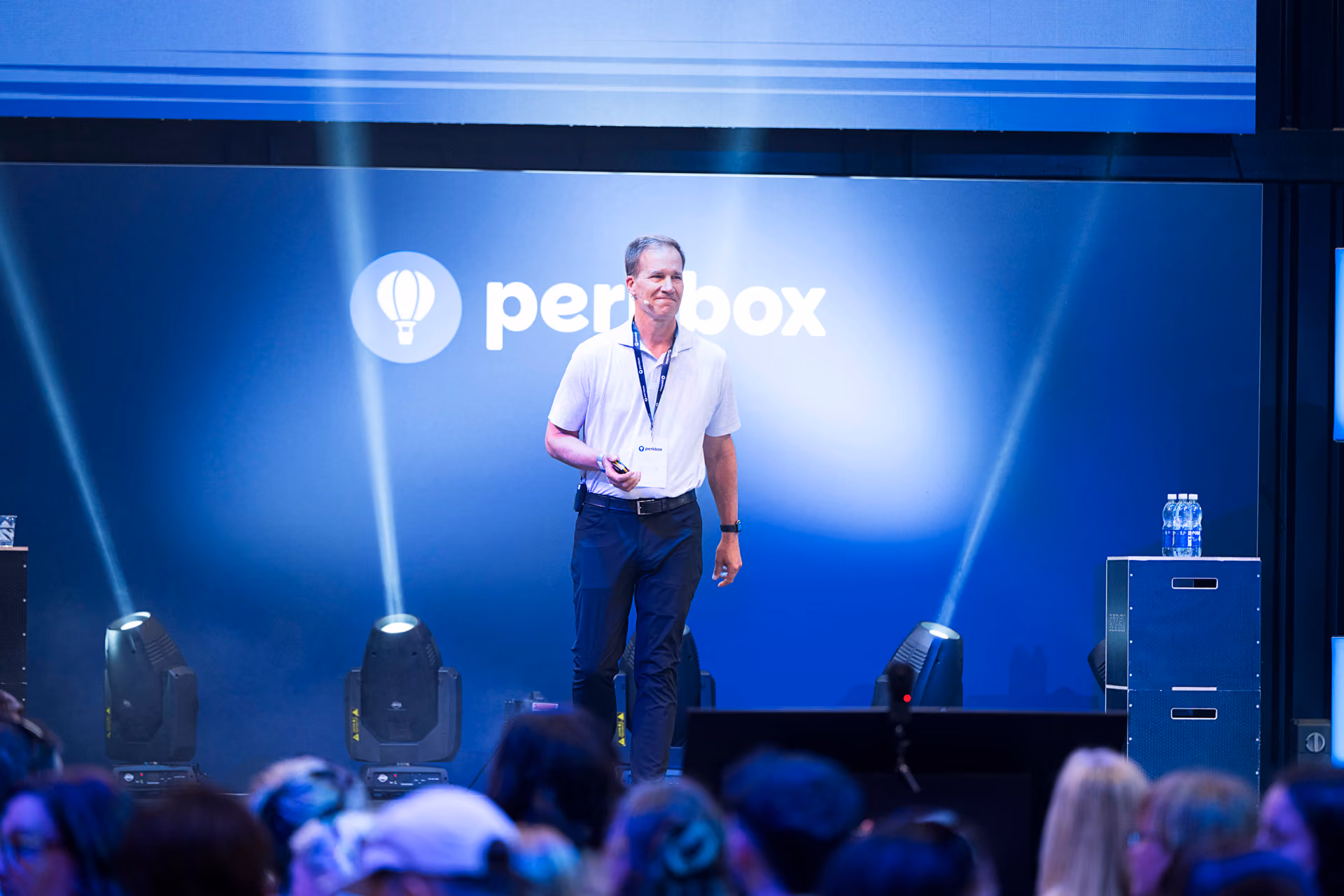 A speaker on stage in front of a large branded screen at a company day