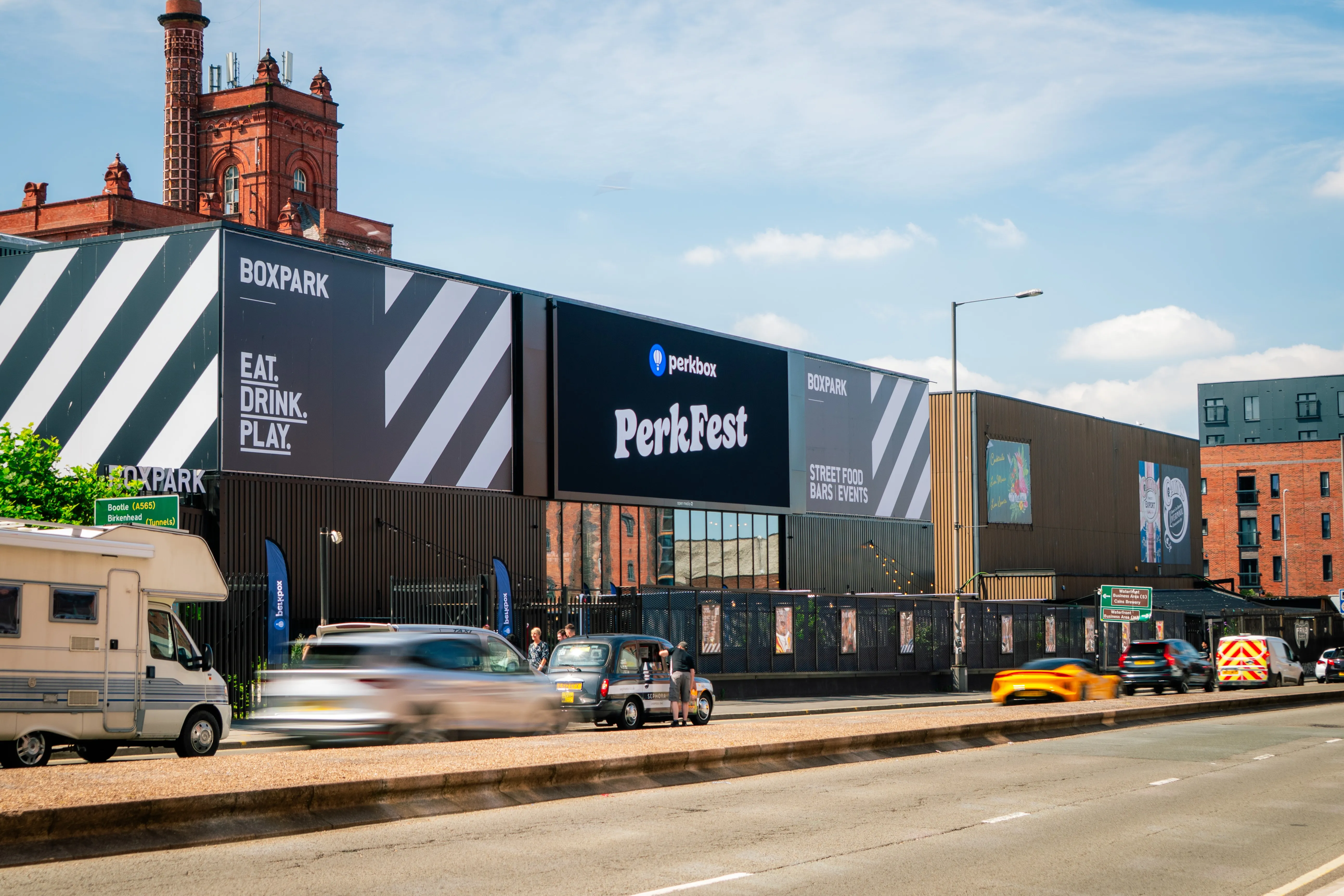 PerkFest signage on the exterior of a Boxpark venue with traffic passing outside