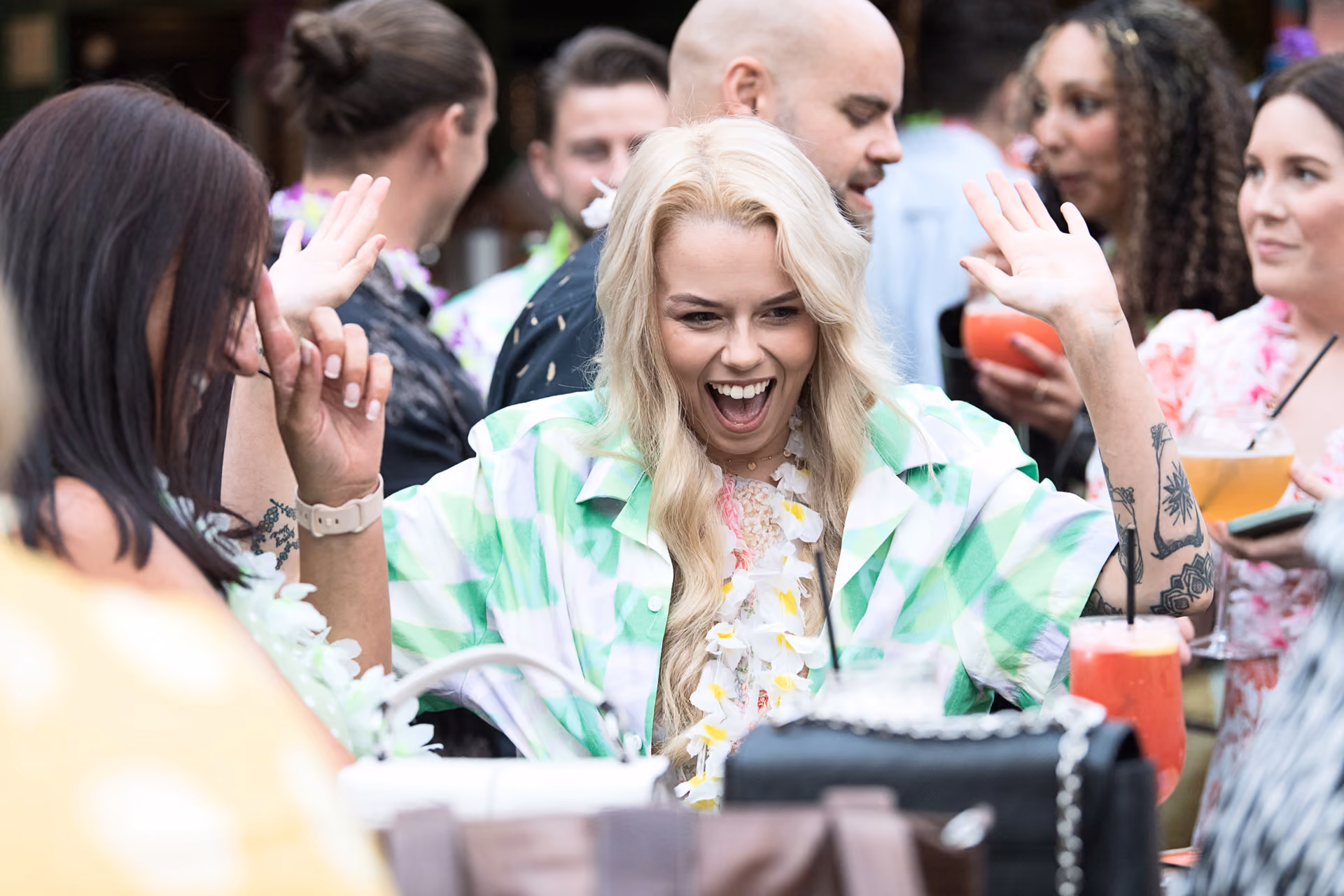 A guest dancing with hands raised among colleagues holding cocktails at a summer party