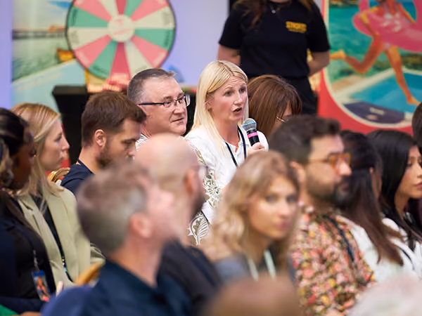 An attendee standing to ask a question into a microphone during an all-hands conference