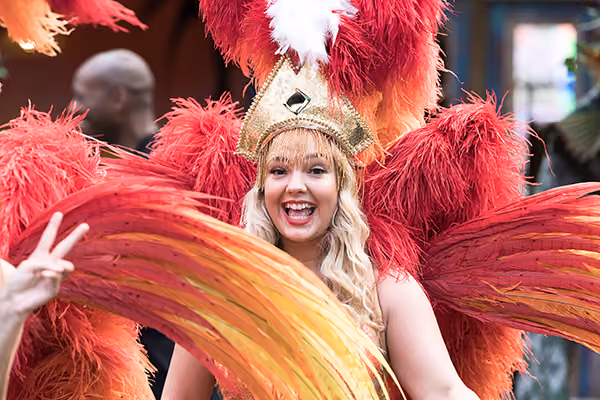 A carnival dancer in a red feathered costume and headdress at a corporate summer event