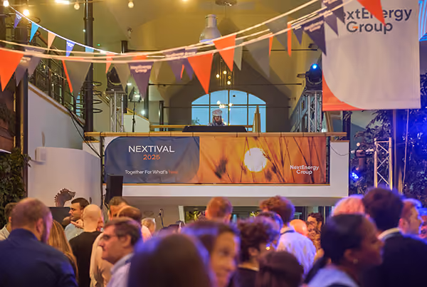 A DJ performing above a busy crowd under bunting at the Nextival 2025 gathering