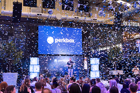 Confetti falling over a crowd in front of a large stage at a company conference