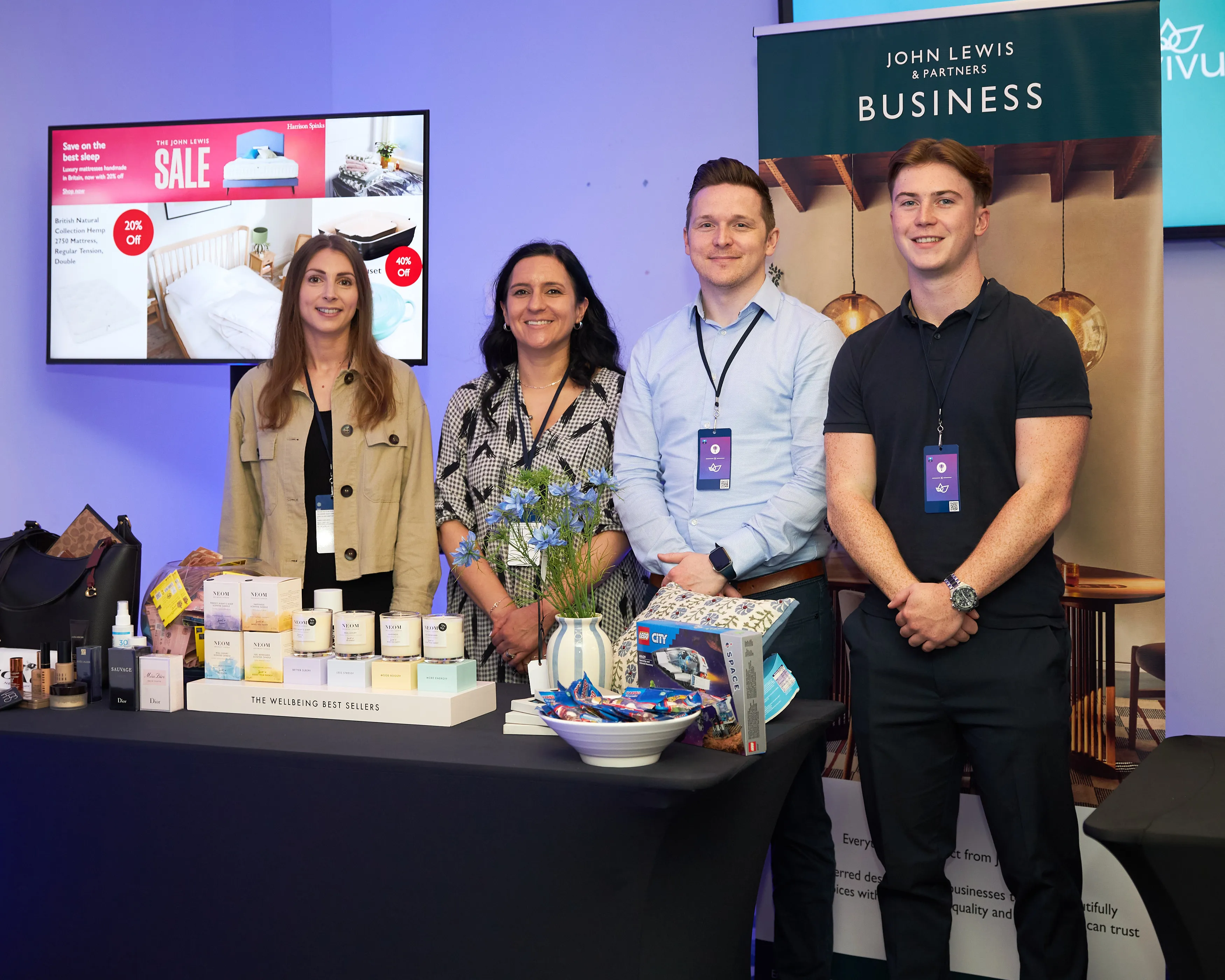 Four exhibitors standing behind a product stand at an employee benefits conference