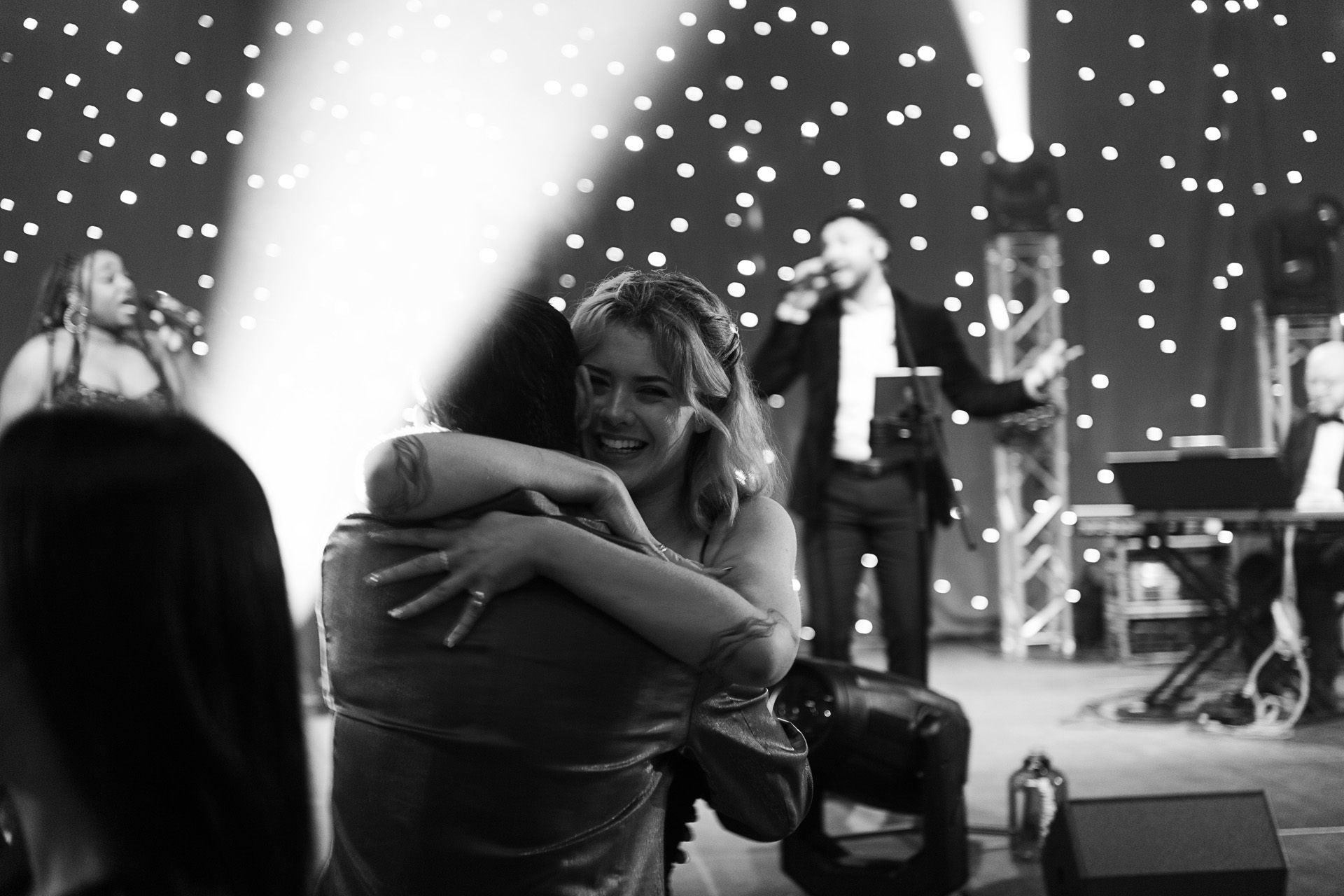 Two colleagues embracing on the dance floor as a live band performs at a company party