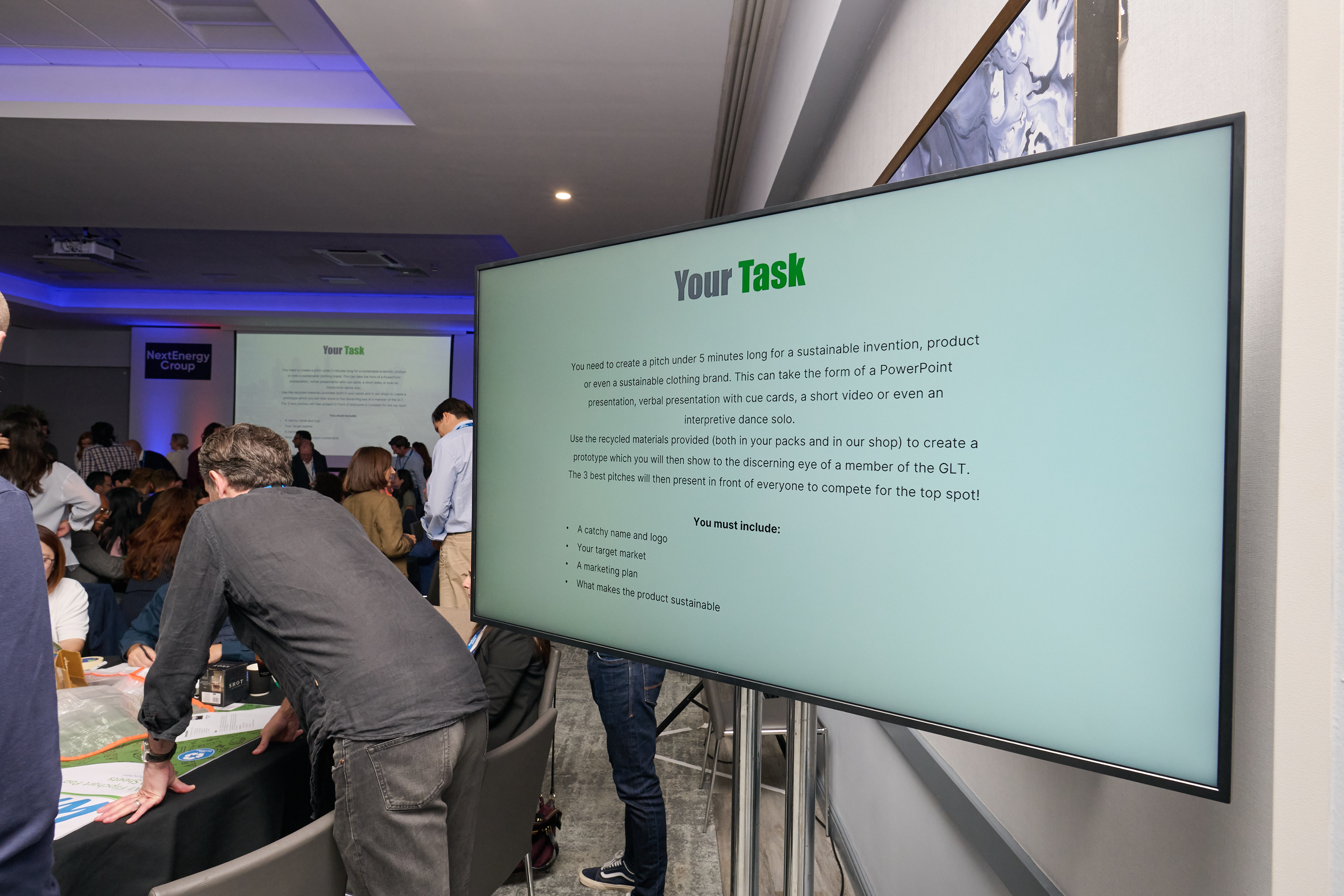 Colleagues gathered around a large screen showing a team task brief during a workshop