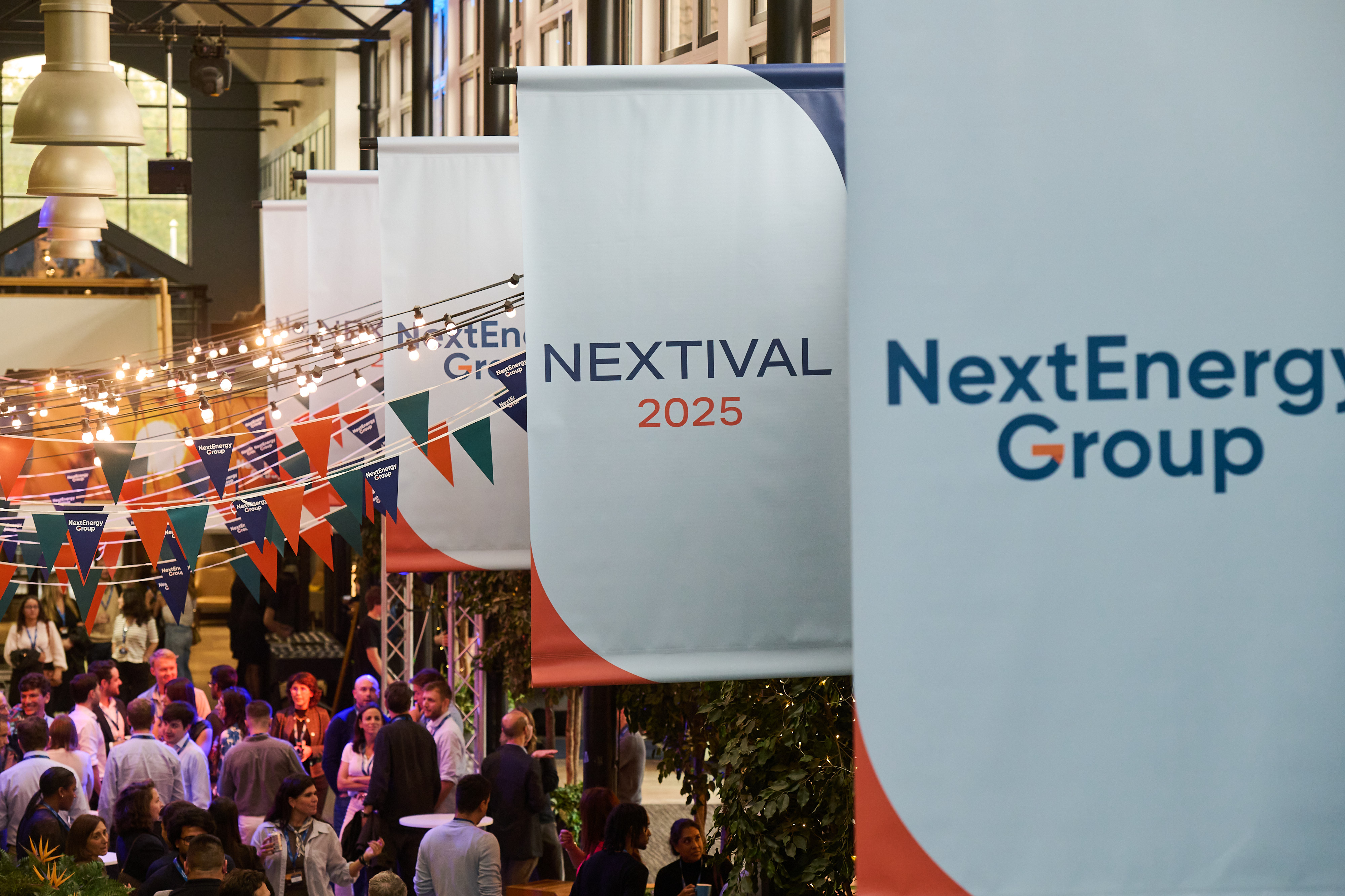 Festival-style branded banners above colleagues mingling under strings of lights and bunting