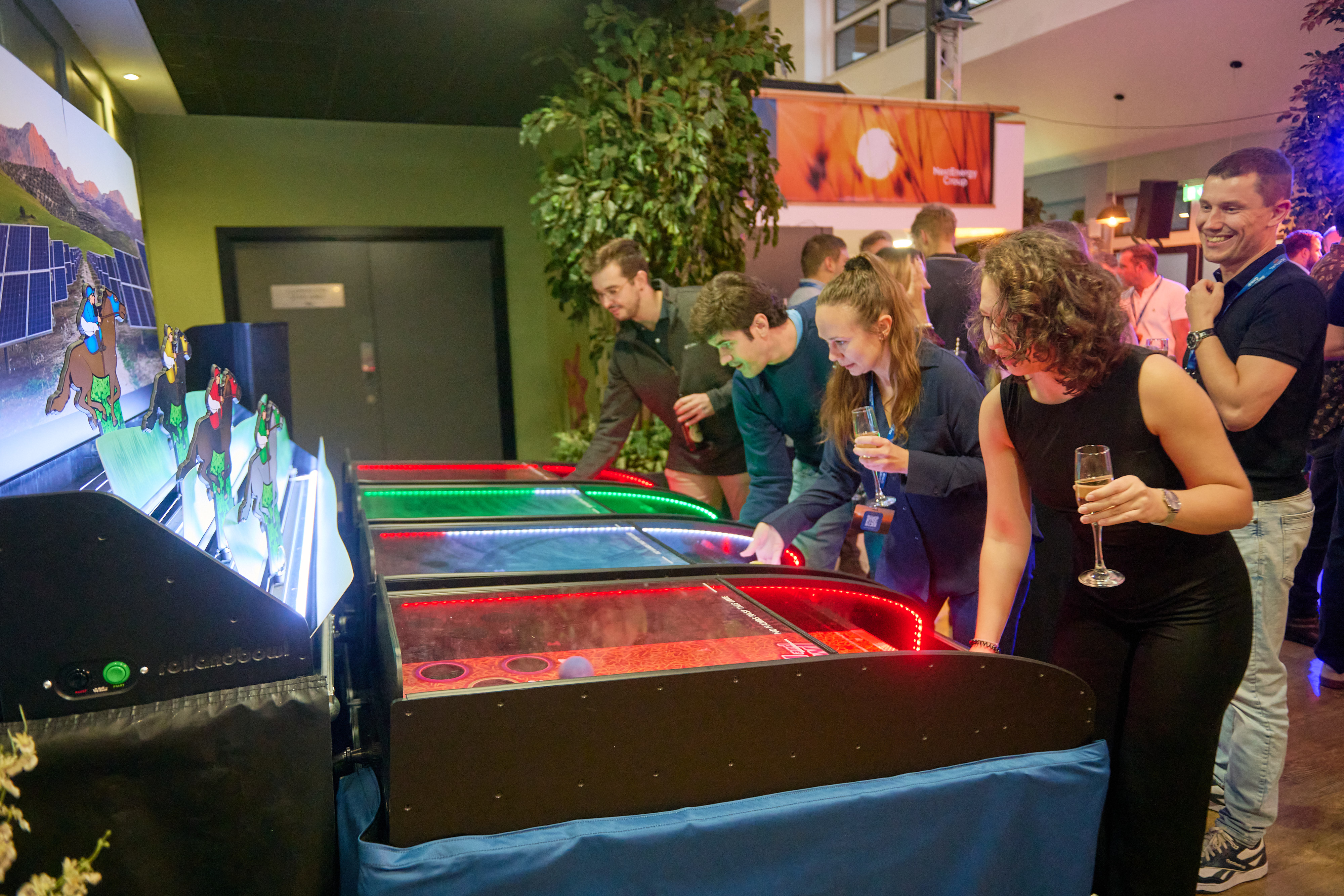 Colleagues queueing to play arcade air hockey machines at an evening away day social