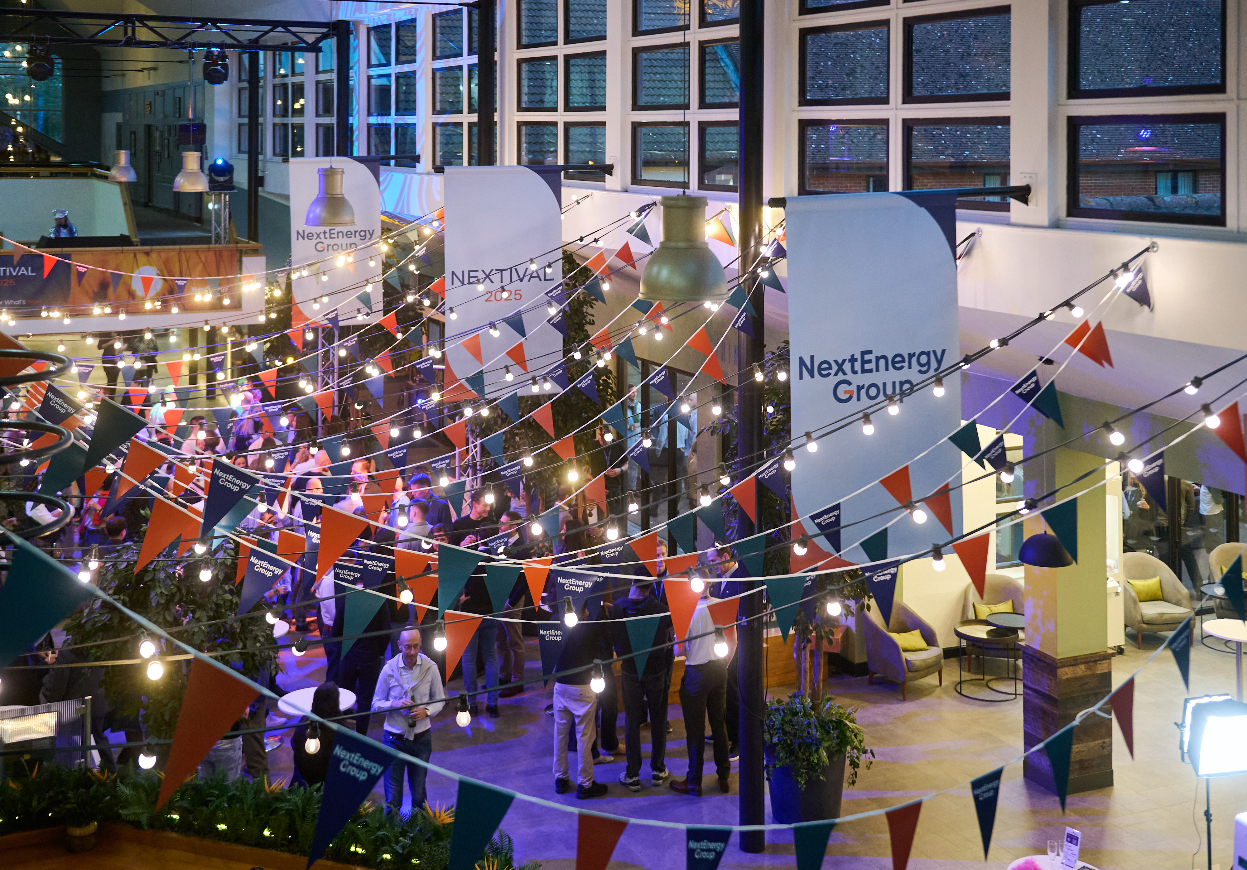 Festoon lights and bunting criss-crossing an office atrium set up for an evening party