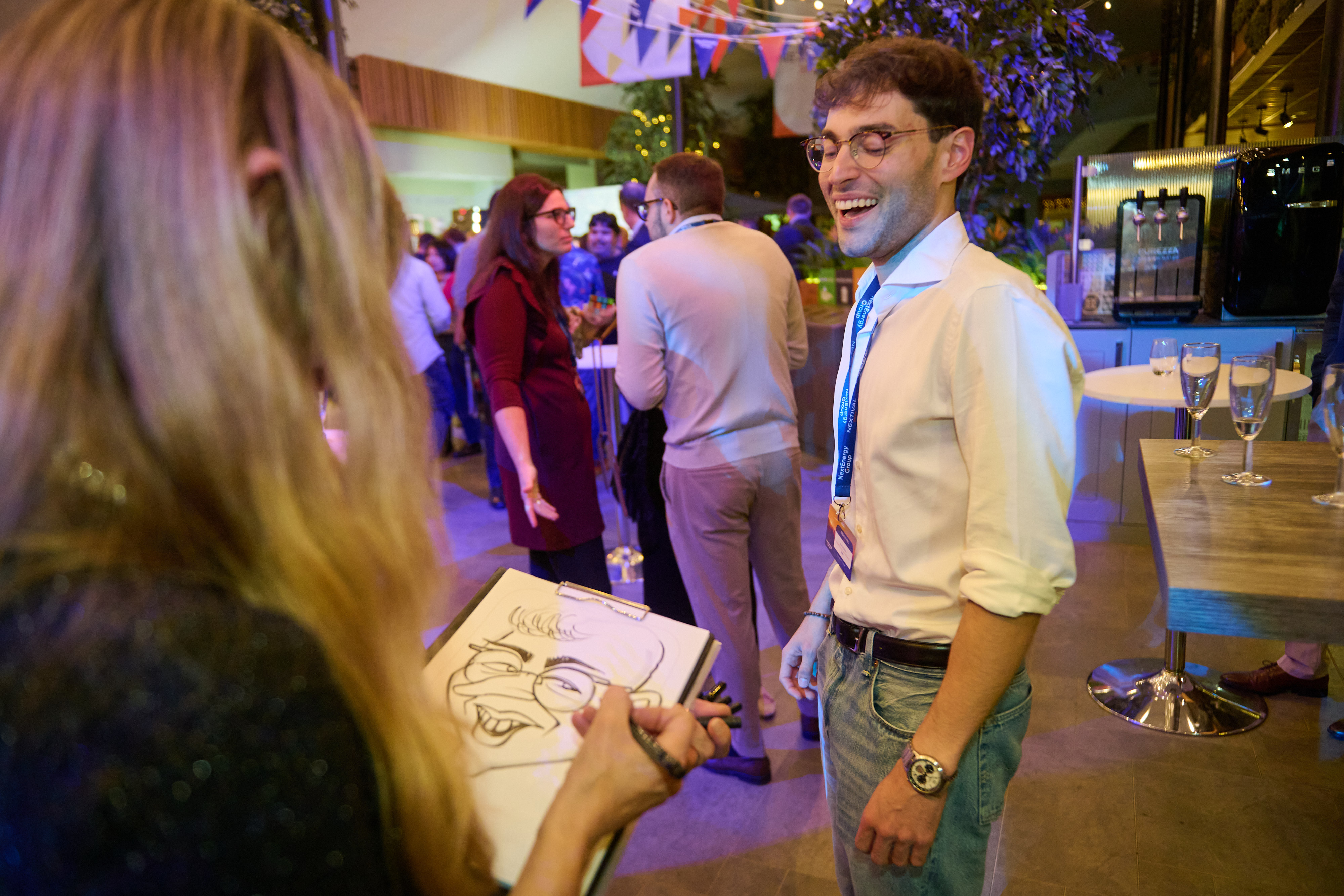 A caricaturist sketching a smiling guest on a pad during a drinks reception