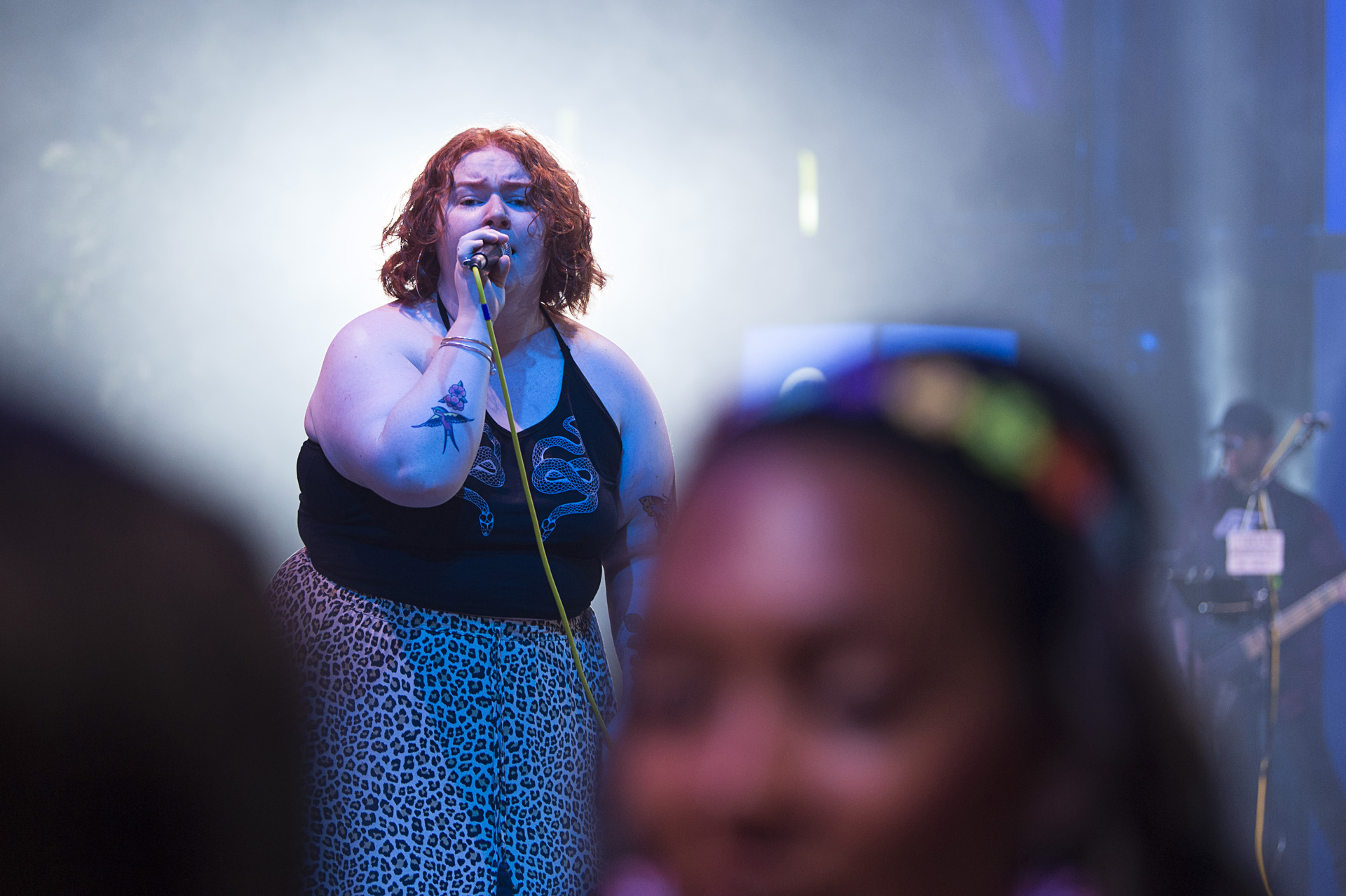 A vocalist singing into a microphone under a spotlight as guests watch from the front