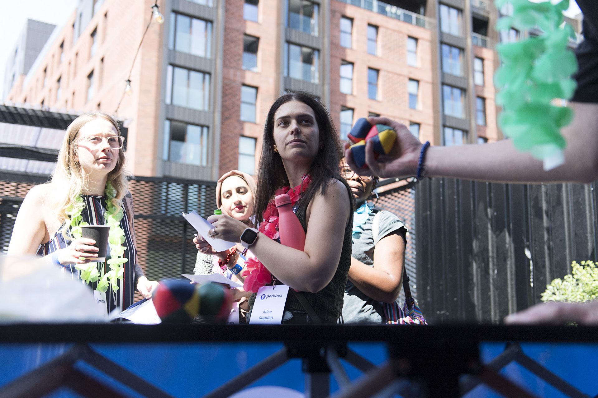 Colleagues in flower garlands gathered on an outdoor terrace during a summer social