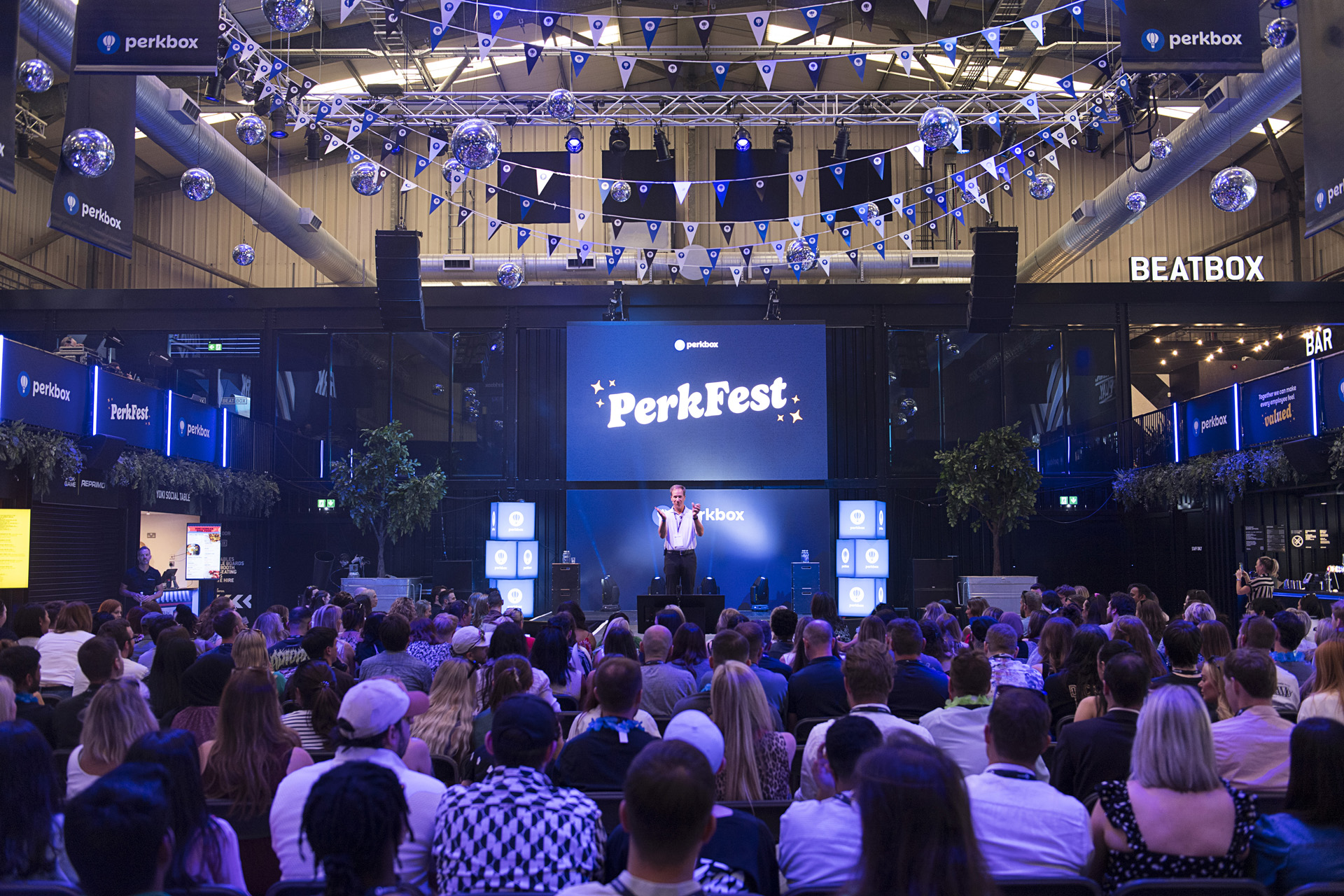 An audience seated facing a stage under disco balls at a brand launch event