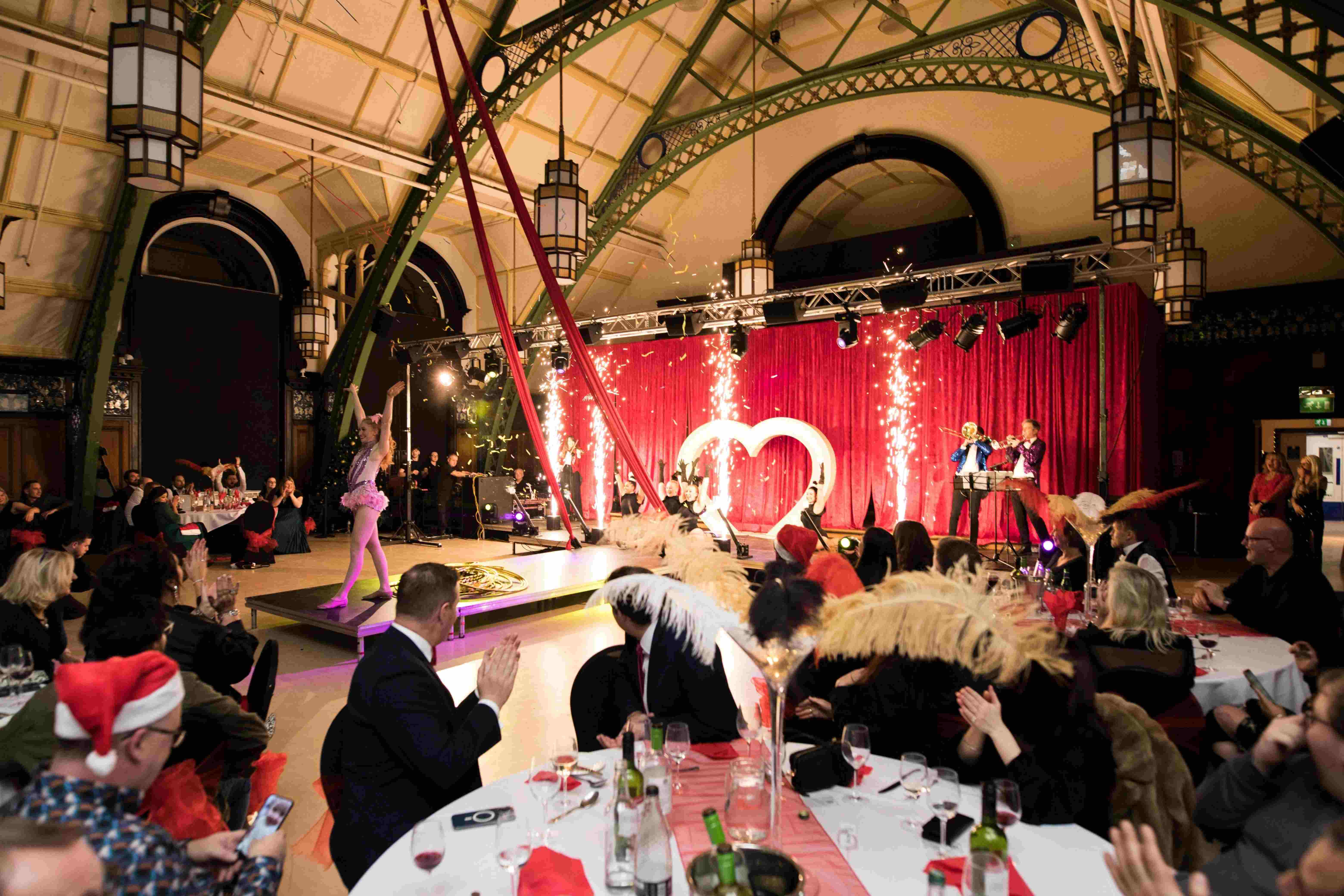 Stage performers and indoor pyrotechnics entertaining guests seated at dressed dinner tables