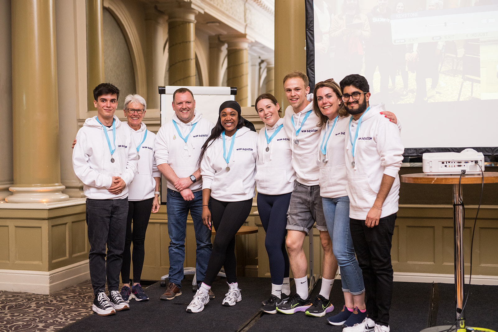 A team in matching hoodies and medals posing together after an away day challenge