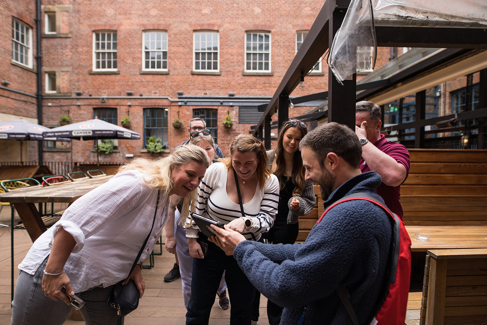 Colleagues crowding around a tablet outdoors while working through a team challenge