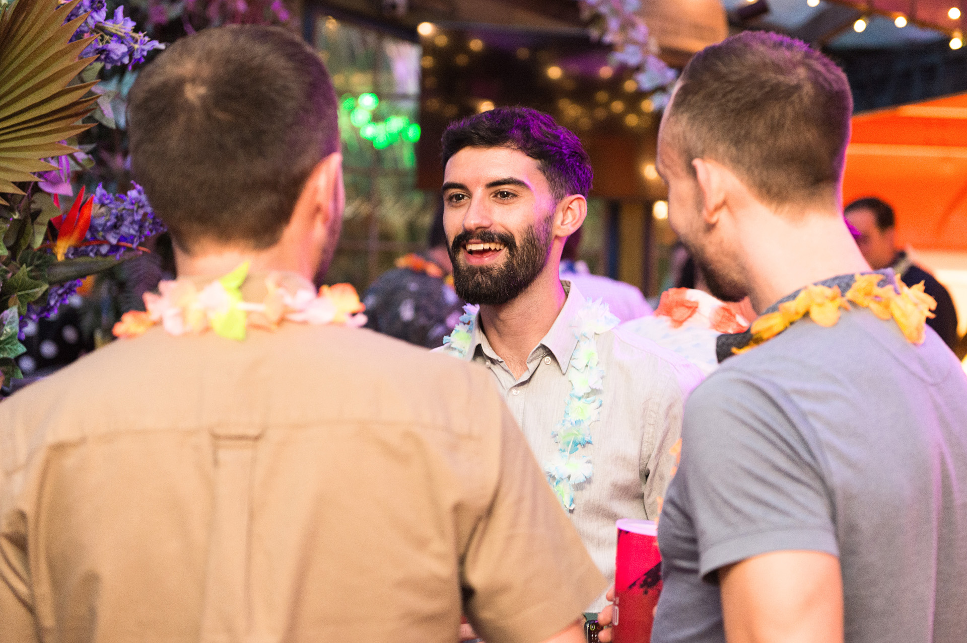 Guests wearing flower garlands talking together at a tropical themed summer party