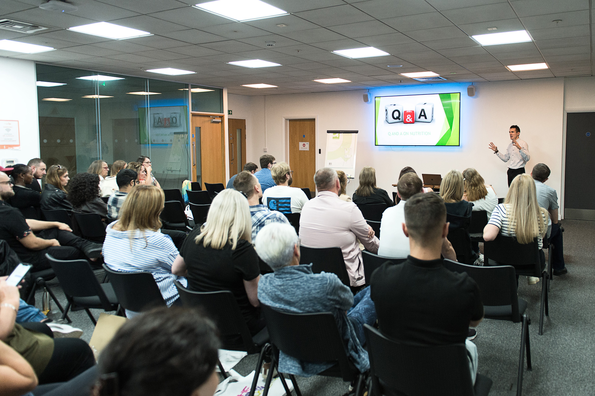 Employees seated for a question and answer session in front of a meeting room screen